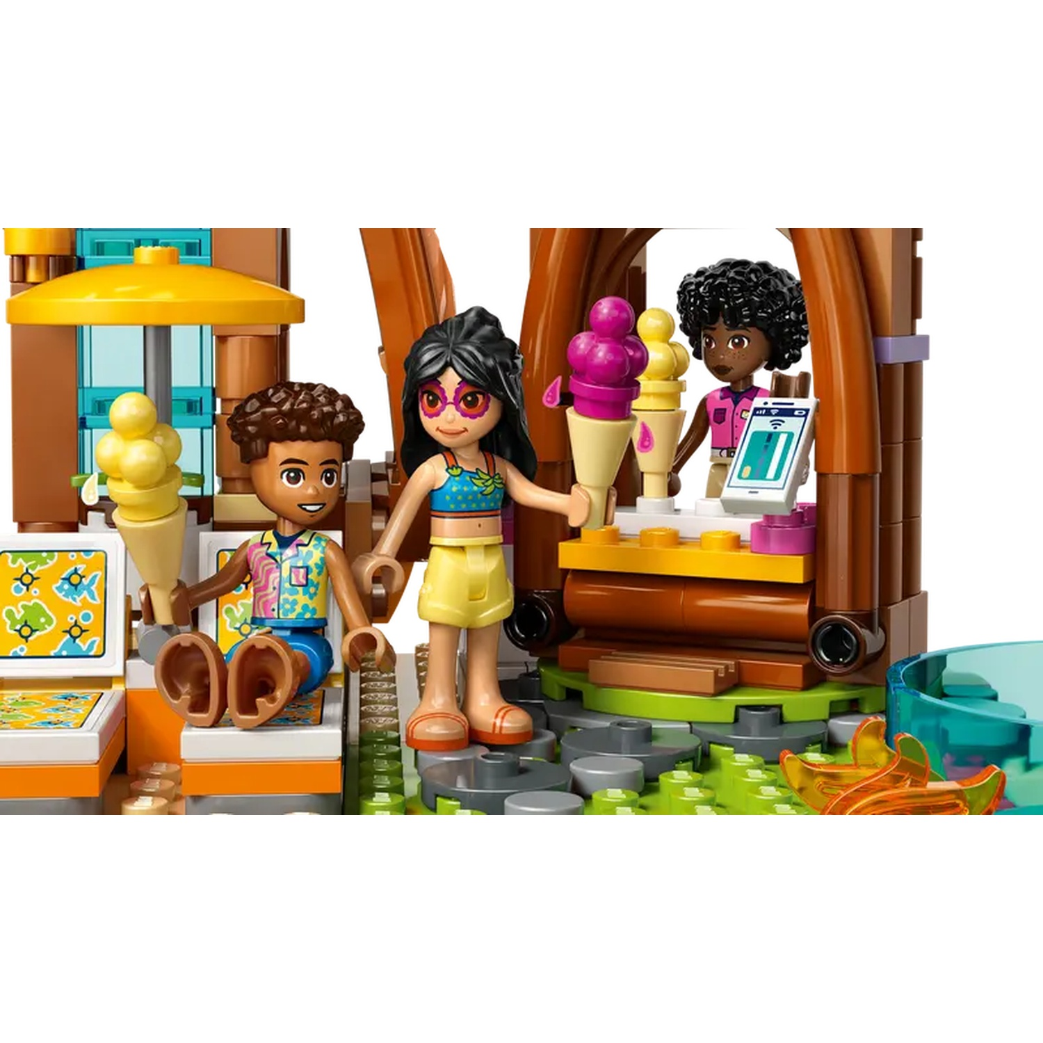 Lego scene: Three figures at an ice cream stand. One holds ice cream, another takes an order. Colorful scene, sunny day.