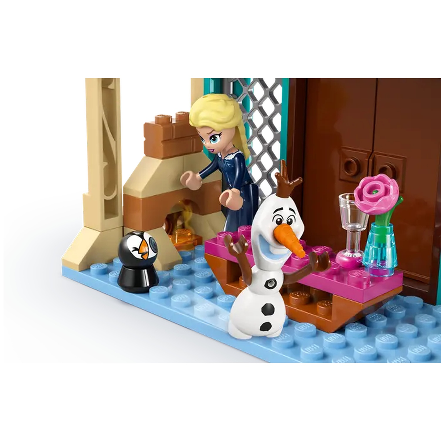 Lego set met Elsa, Olaf en een pinguïn. Een tafel met een roos en glazen. Achtergrond is een bruine deur.