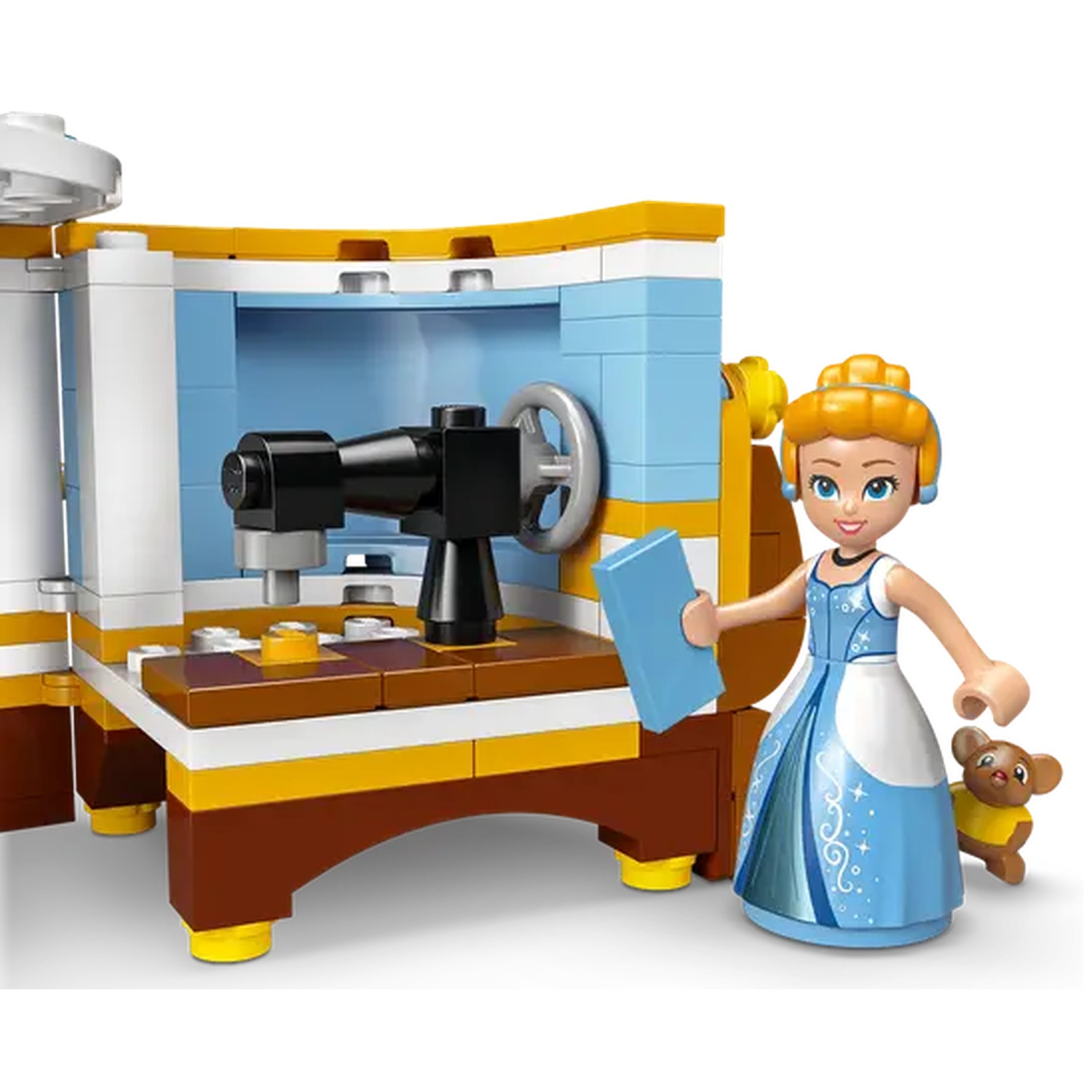Een Lego-set met Assepoester en een naaimachine. Assepoester houdt een blauw boek vast, en een beer staat naast haar.