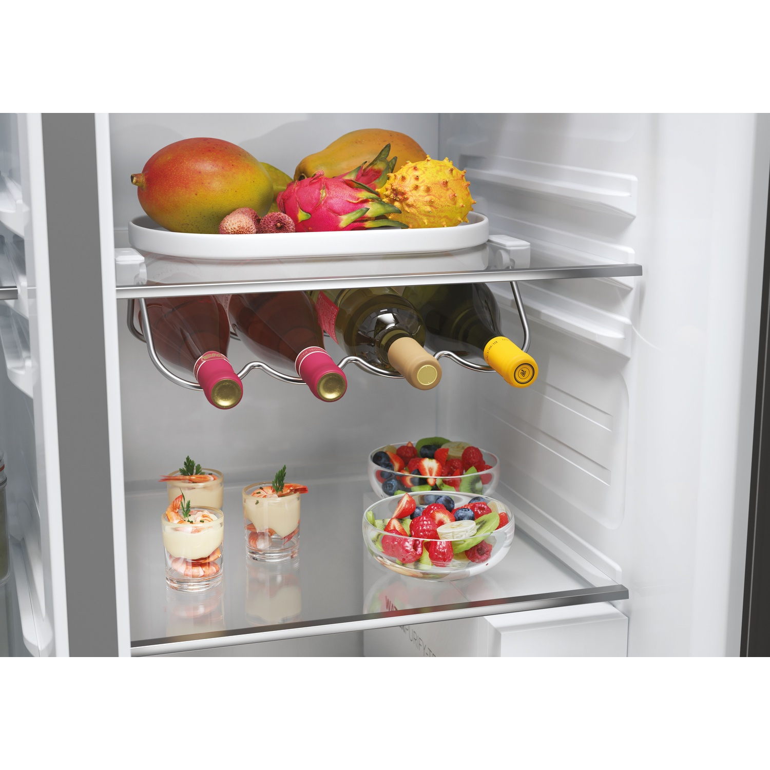 All'interno di un frigorifero, frutta e bottiglie di vino sono visibili sugli scaffali. Ci sono anche piccoli bicchieri con antipasti e ciotole di frutta.