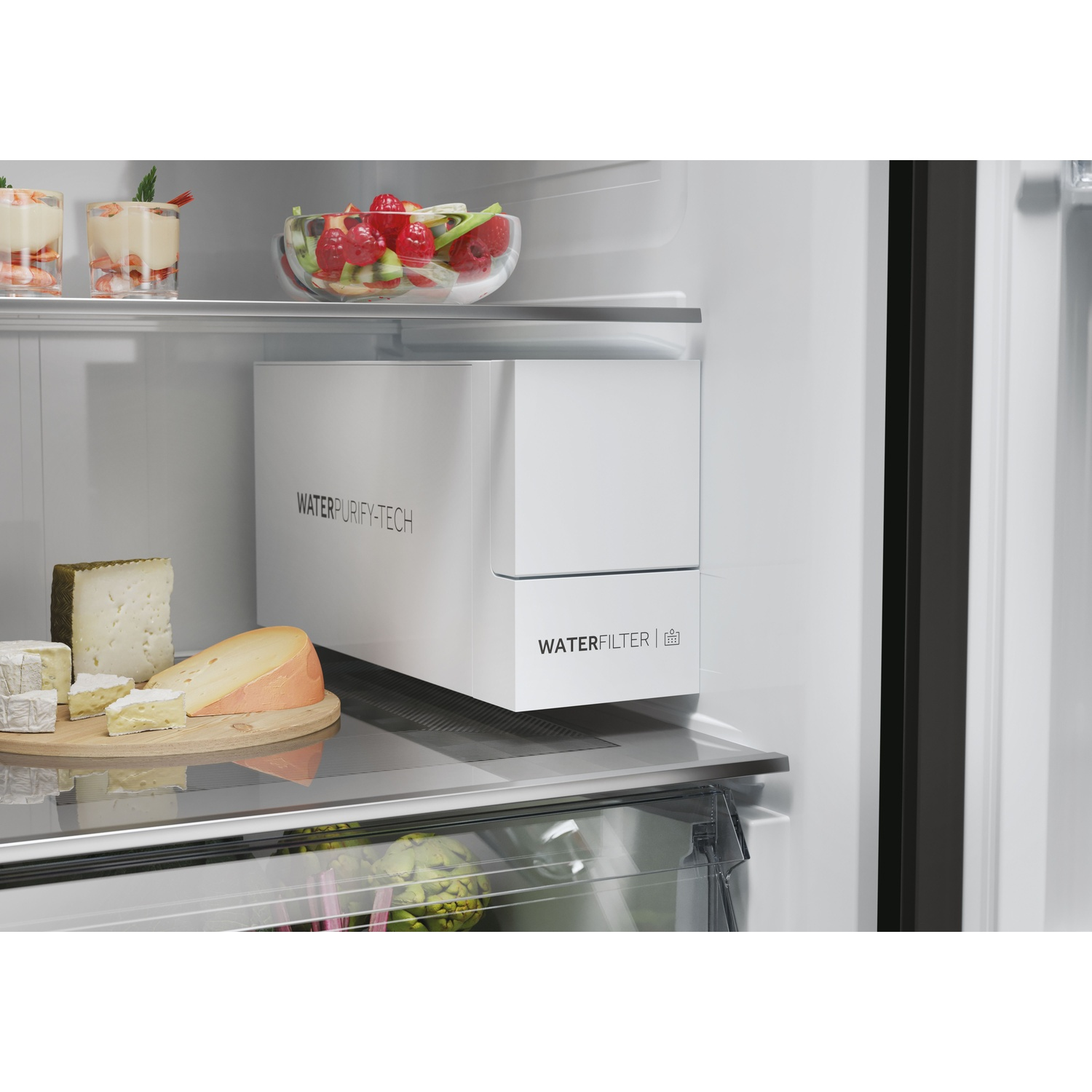 Dentro un frigo: formaggio su un tagliere, frutta in una ciotola, un filtro dell'acqua e dessert in bicchieri.