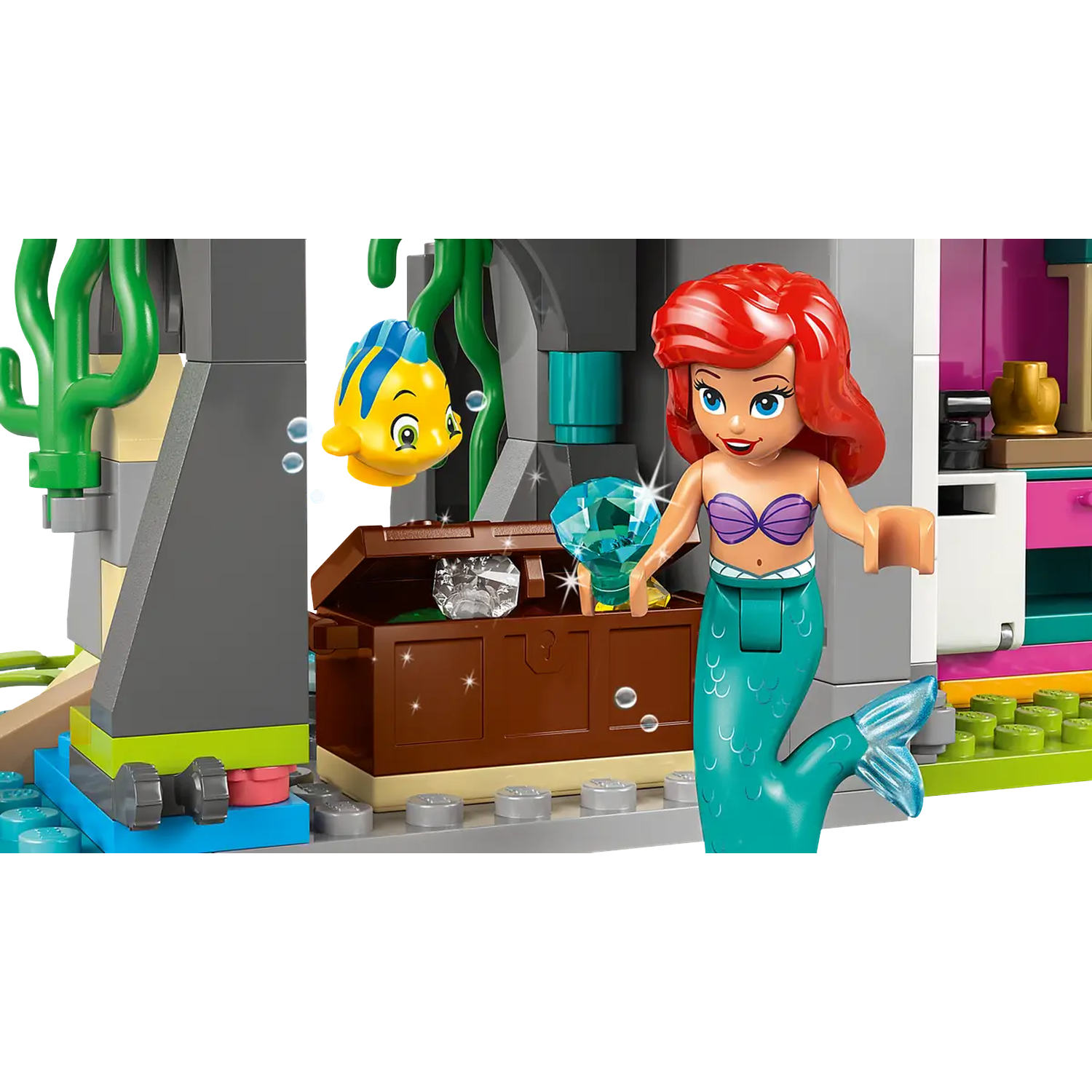 Ariël, een zeemeermin, staat bij een open schatkist met juwelen. Botje zwemt in de buurt. De scène is een Lego-set met een kleurrijke achtergrond.