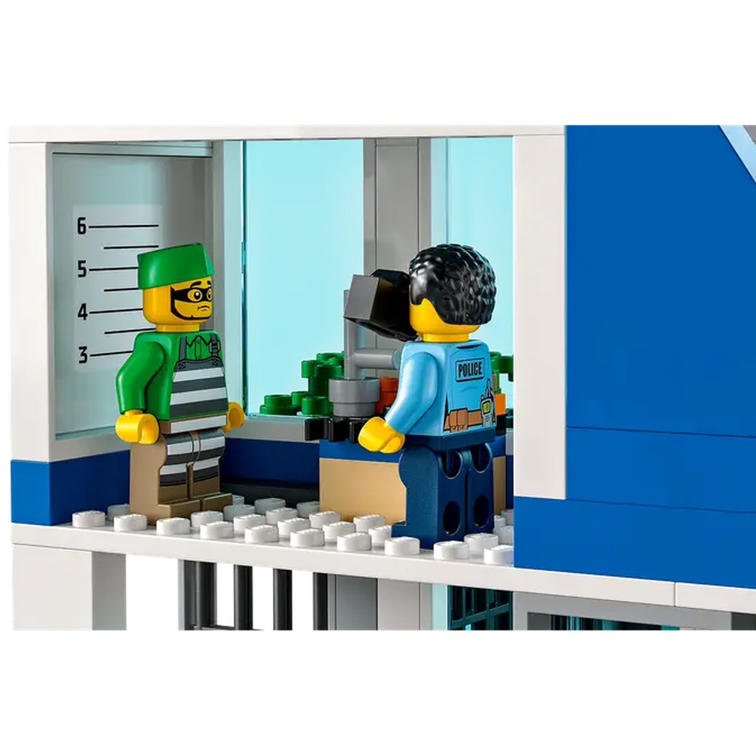 Lego scene: A prisoner in striped clothes and a police officer. A scale is on the wall. A blue building is on the right.