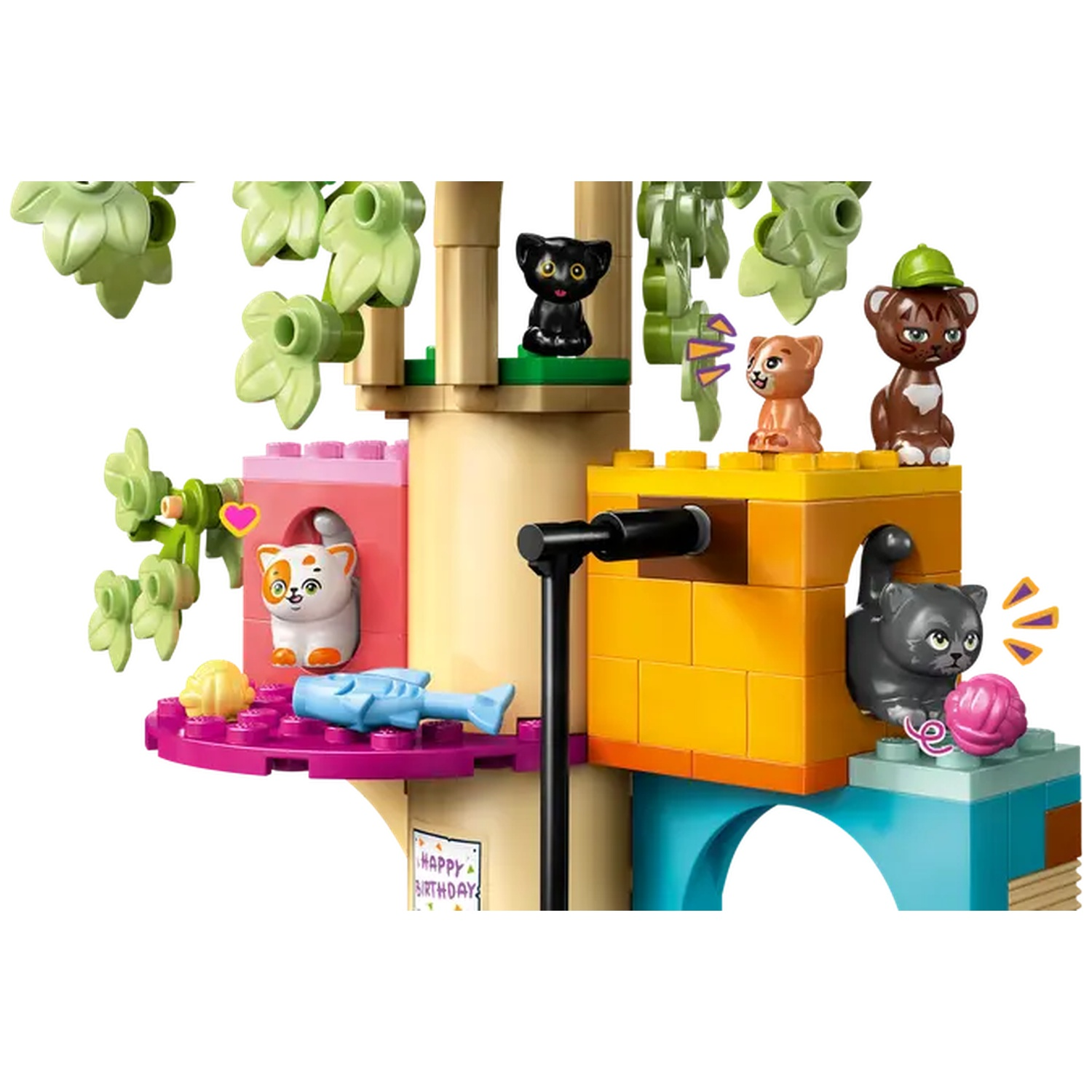A Lego set with several cat figures on a colorful building with trees and leaves. Includes a pink yarn ball.
