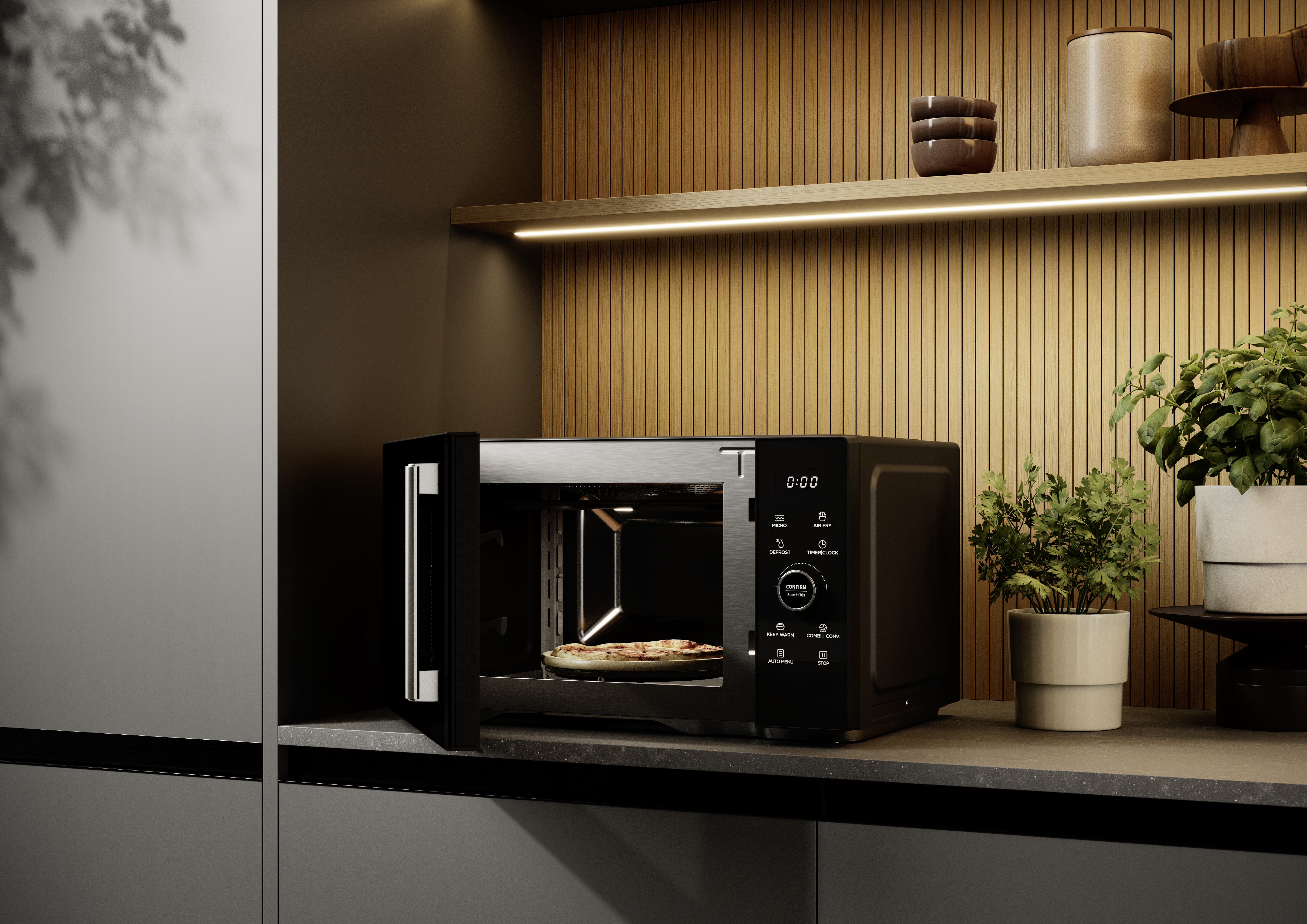 Czarna kuchenka mikrofalowa z otwartymi drzwiami, pokazująca pizzę w środku. Stoi na blacie. Tło to drewniana ściana i rośliny.