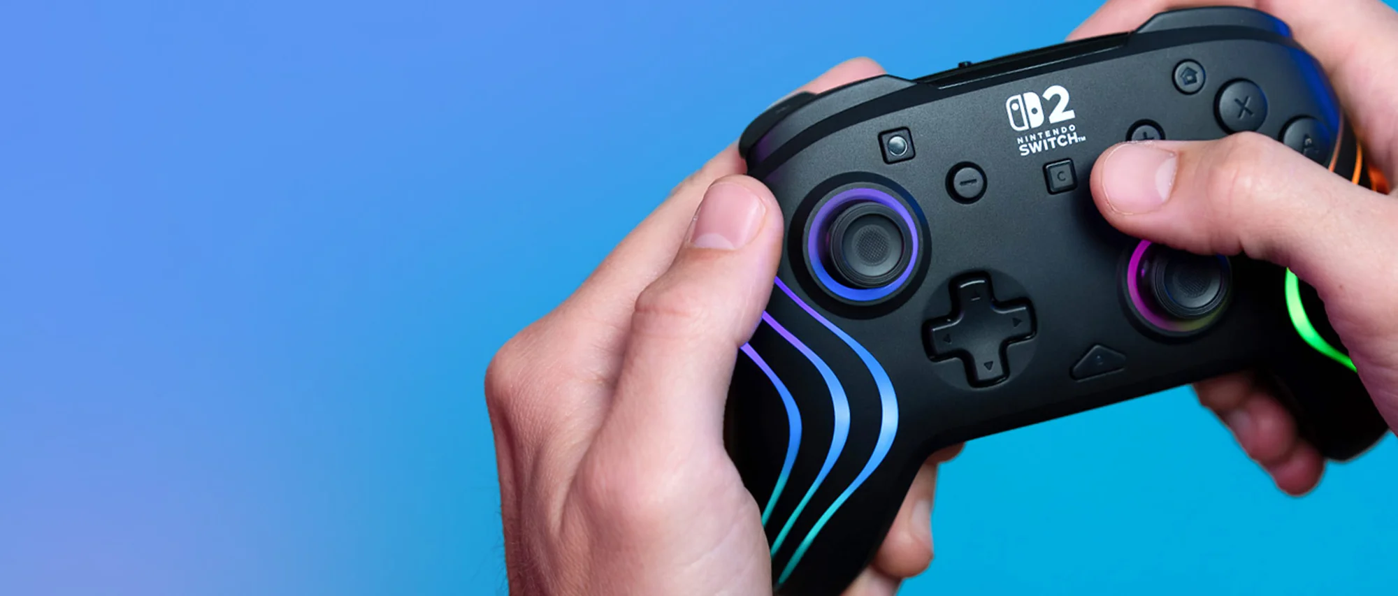 Hände halten einen schwarzen Nintendo Switch-Controller mit bunten Lichtern vor blauem Hintergrund.