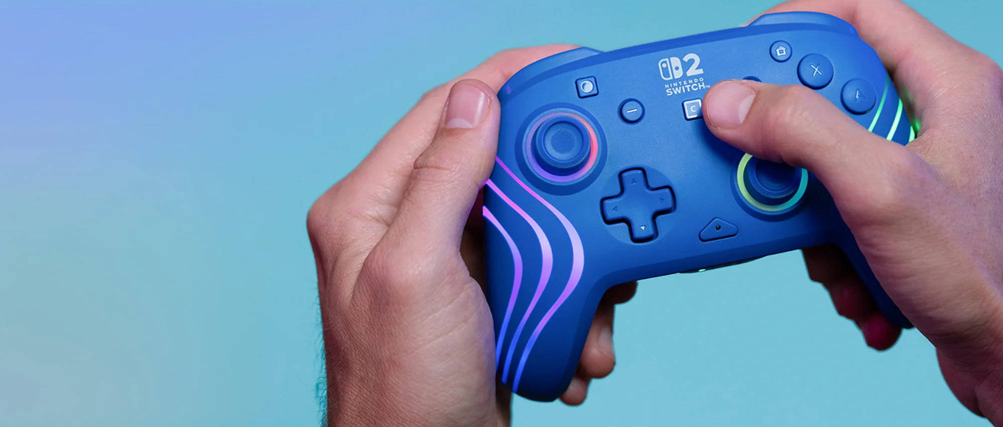 Mani che tengono un controller Nintendo Switch blu. Ha luci e pulsanti colorati. Lo sfondo è blu e viola.