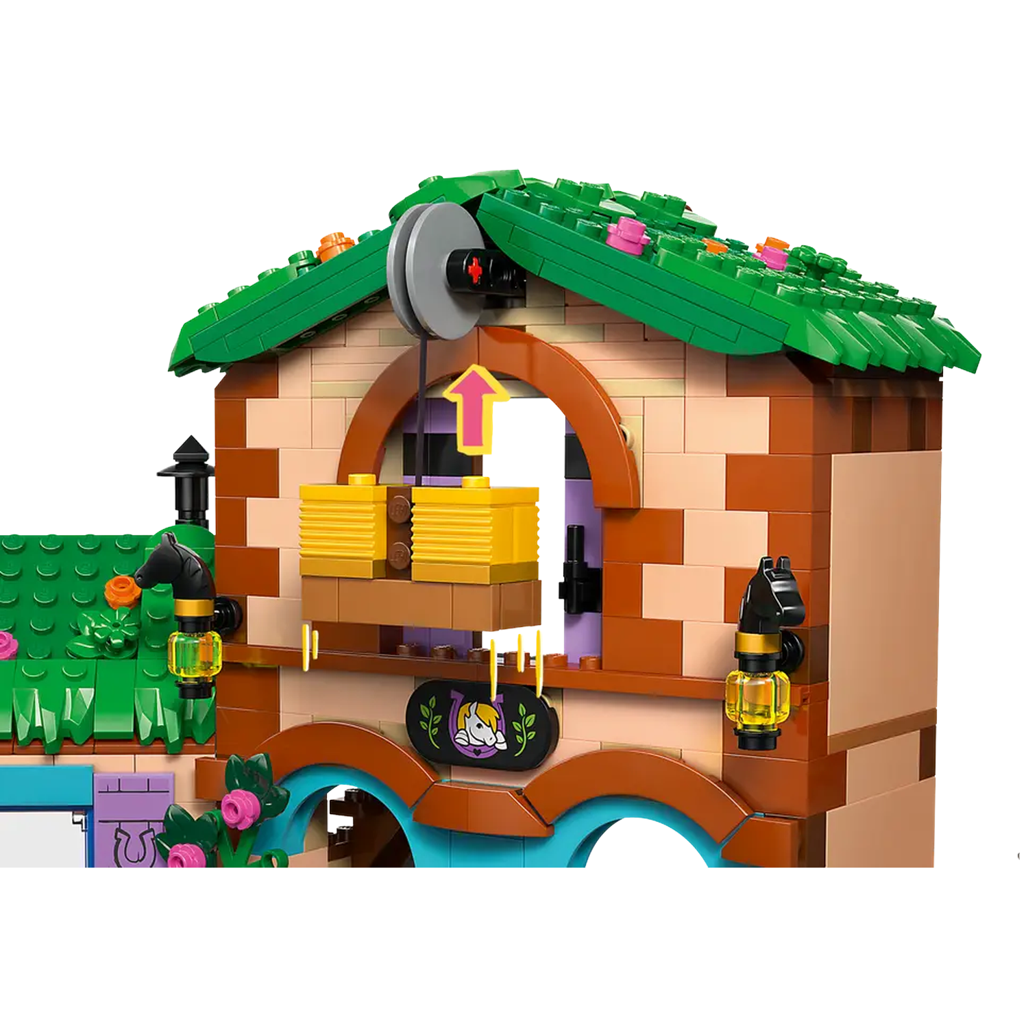 A Lego building with green roof, brown and beige walls, and a pulley system lifting yellow blocks. Pink flowers and a sign are visible.