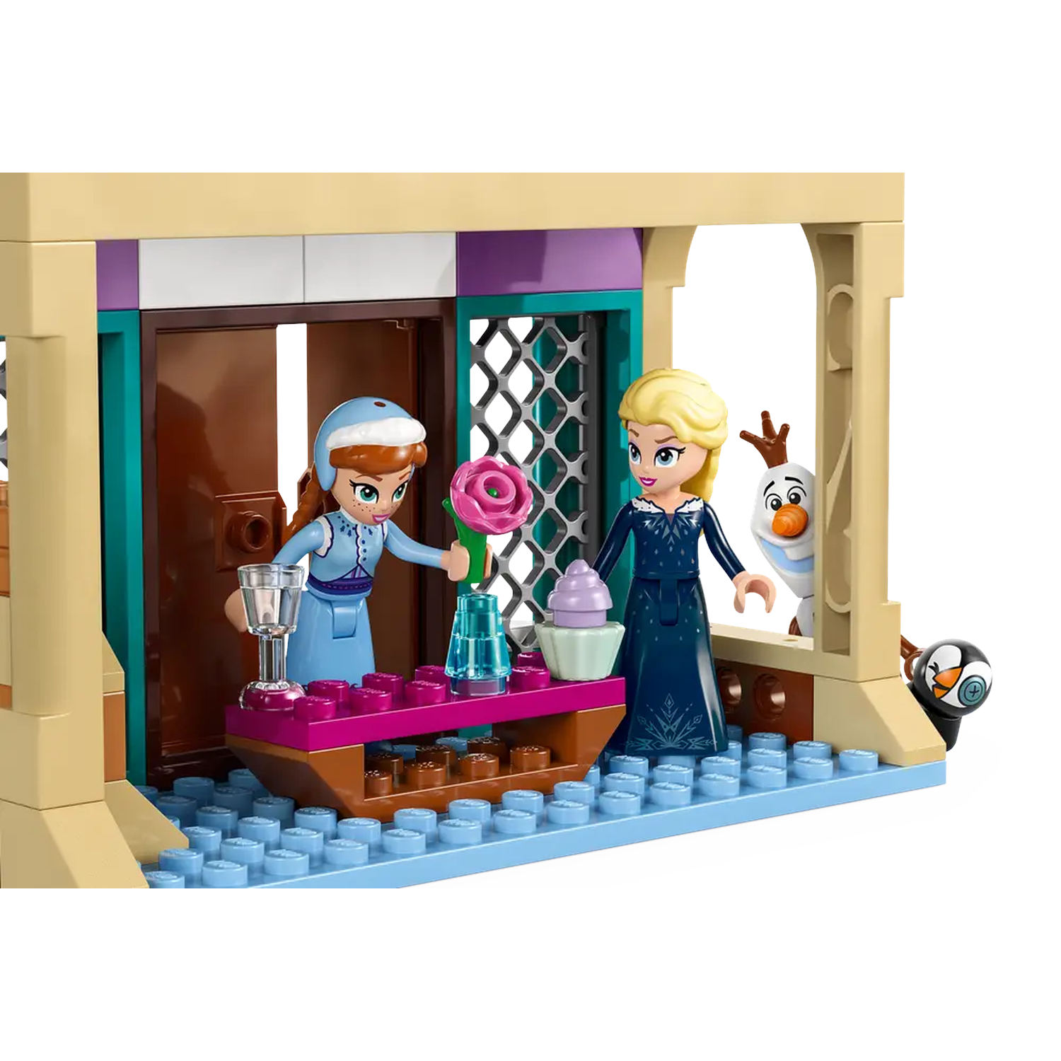 Lego set depicting Anna and Elsa from Frozen. Olaf and a penguin are also present. A table has a rose, a cupcake, and a glass.