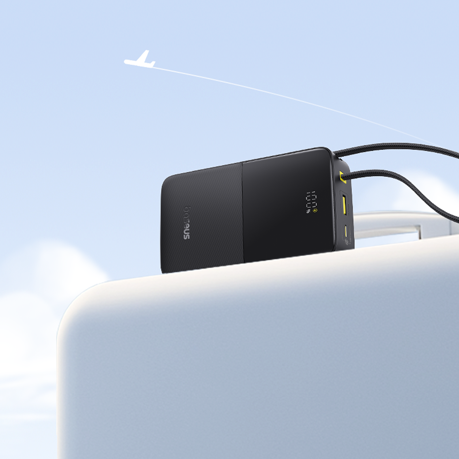 Un power bank negro con pantalla digital mostrando 100%. Un avión blanco vuela en el cielo azul.