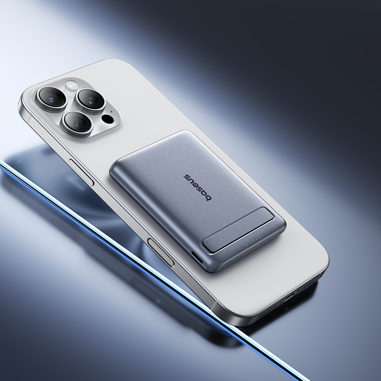 Un iPhone plateado con un banco de energía gris adjunto. El banco de energía tiene la palabra 'baseus'. El fondo es un degradado.