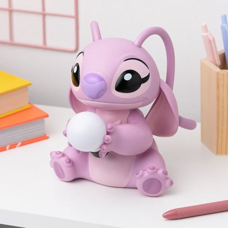 Una figura rosa de Angel sosteniendo un orbe blanco. La figura está sobre un escritorio blanco, con bolígrafos y libros en el fondo.