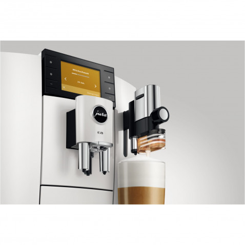 Biały ekspres do kawy Jura E8 dozuje kawę do szklanki. Ekran wyświetla ustawienia, czarno-srebrny design.