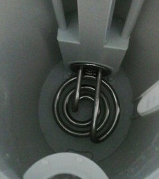 Wnętrze białego czajnika. Srebrna spirala grzewcza na dole, z plastikowymi wspornikami powyżej.