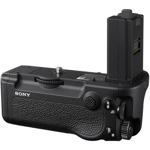 Siyah bir Sony kamera tutacağı gösteriliyor. Düğmeleri, kadranları ve dokulu bir yüzeyi var. Yan tarafta bir pil bölmesi görülüyor.