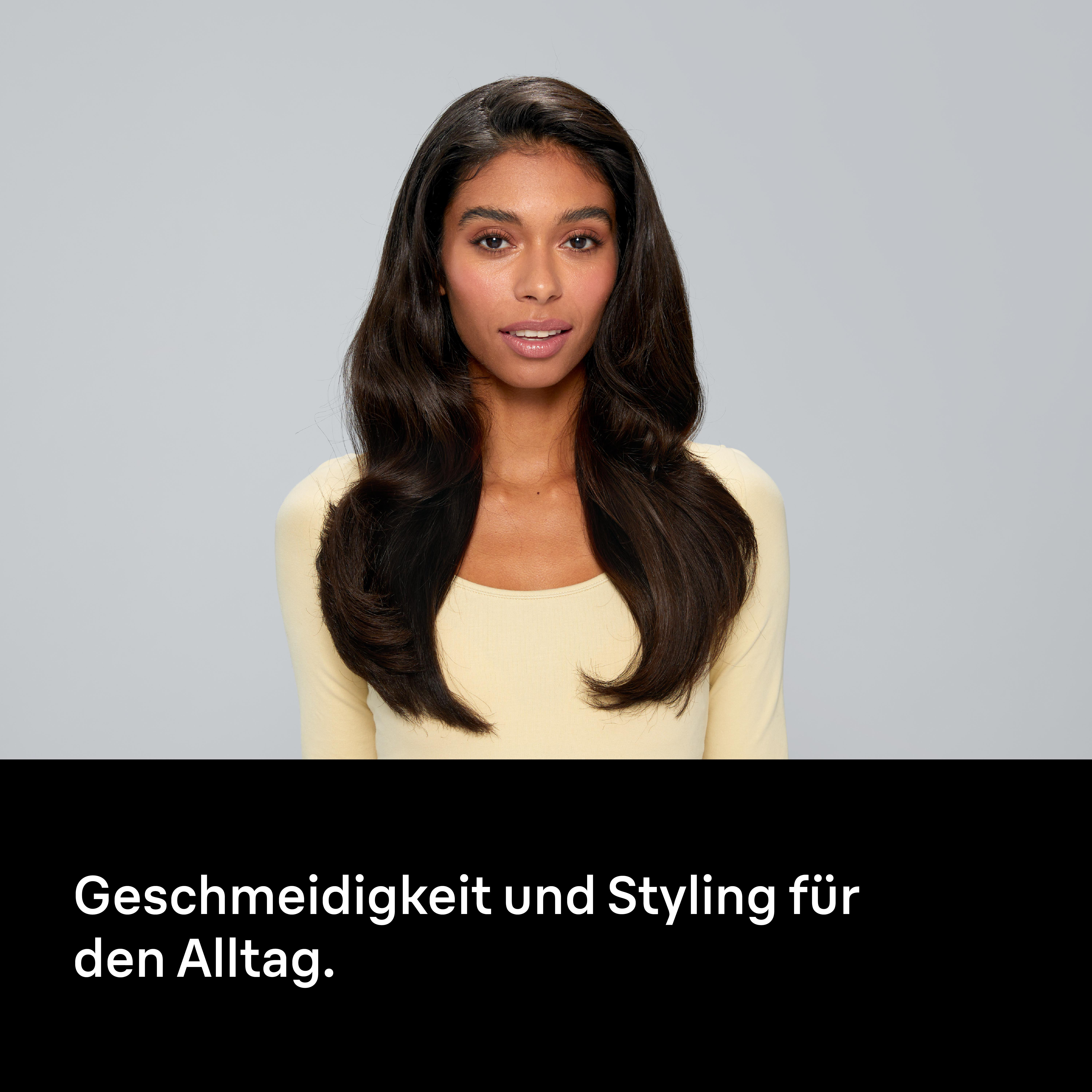 Eine Frau mit dunklem Haar und einem gelben Oberteil blickt in die Kamera. Der Hintergrund ist grau. Text unten.
