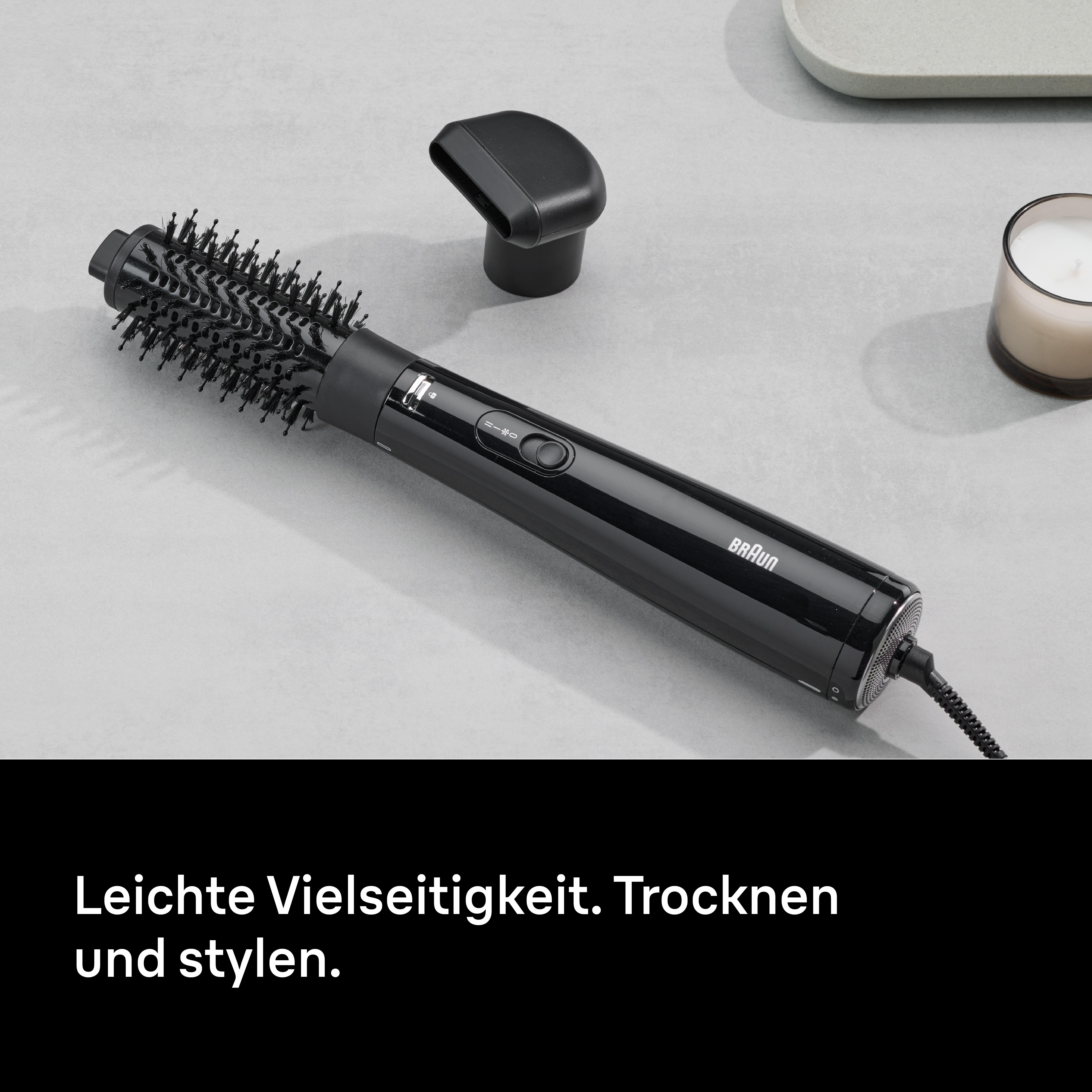Schwarzer Haarstyler auf grauer Oberfläche. Enthält Düse, Tablett und Kerze. Braun-Logo sichtbar. Text: Leicht, Trocknen und stylen.