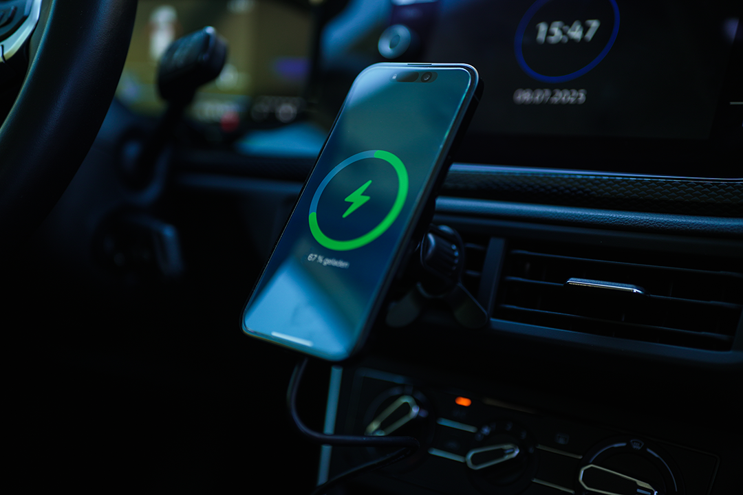 Egy telefon töltődik egy autóban. A képernyő 67%-os töltési szimbólumot mutat. Az idő 15:47. A telefon egy tartóra van szerelve.