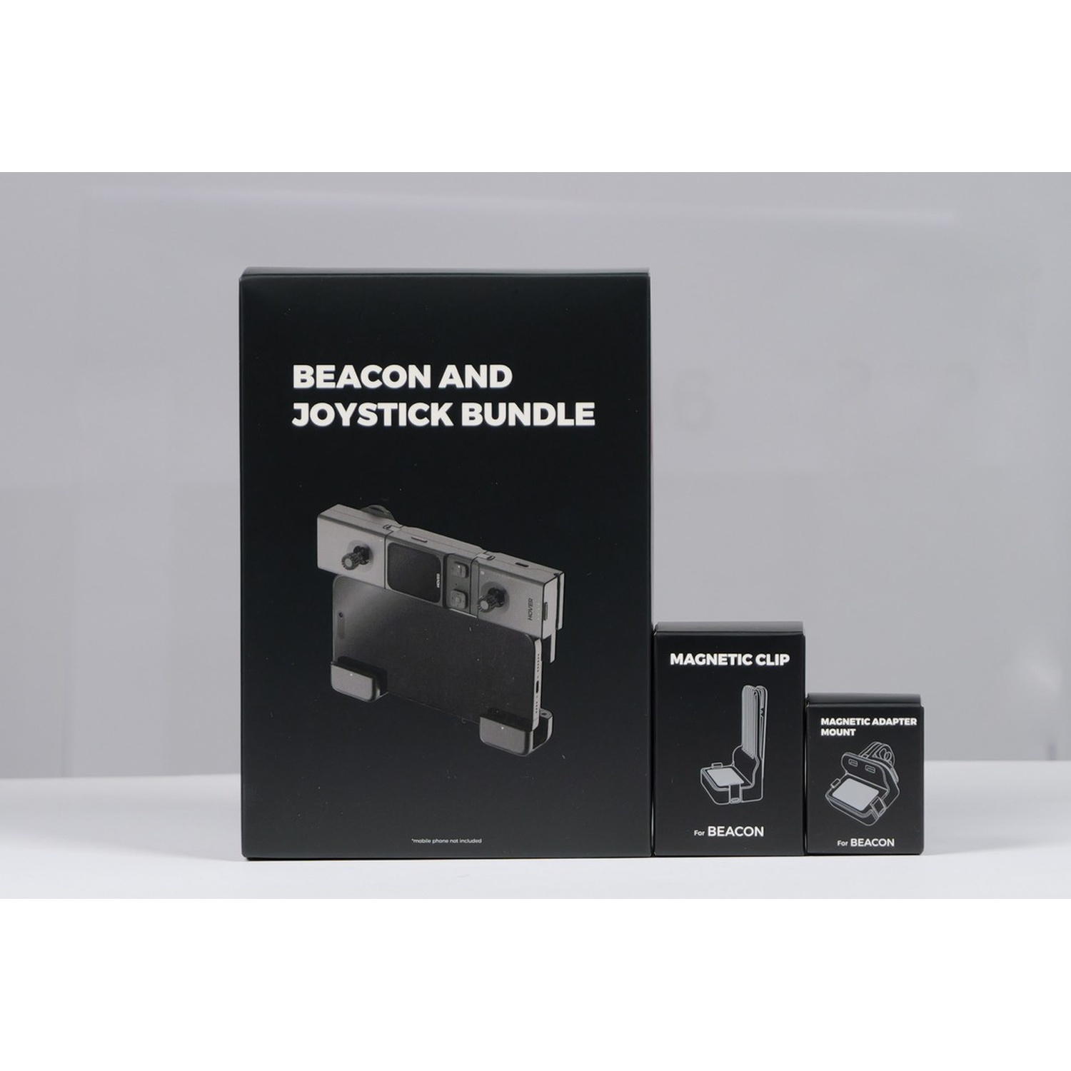 Scatole nere con nomi di prodotti: Beacon and Joystick Bundle, Magnetic Clip e Magnetic Adapter Mount. Un supporto per telefono è in una scatola.