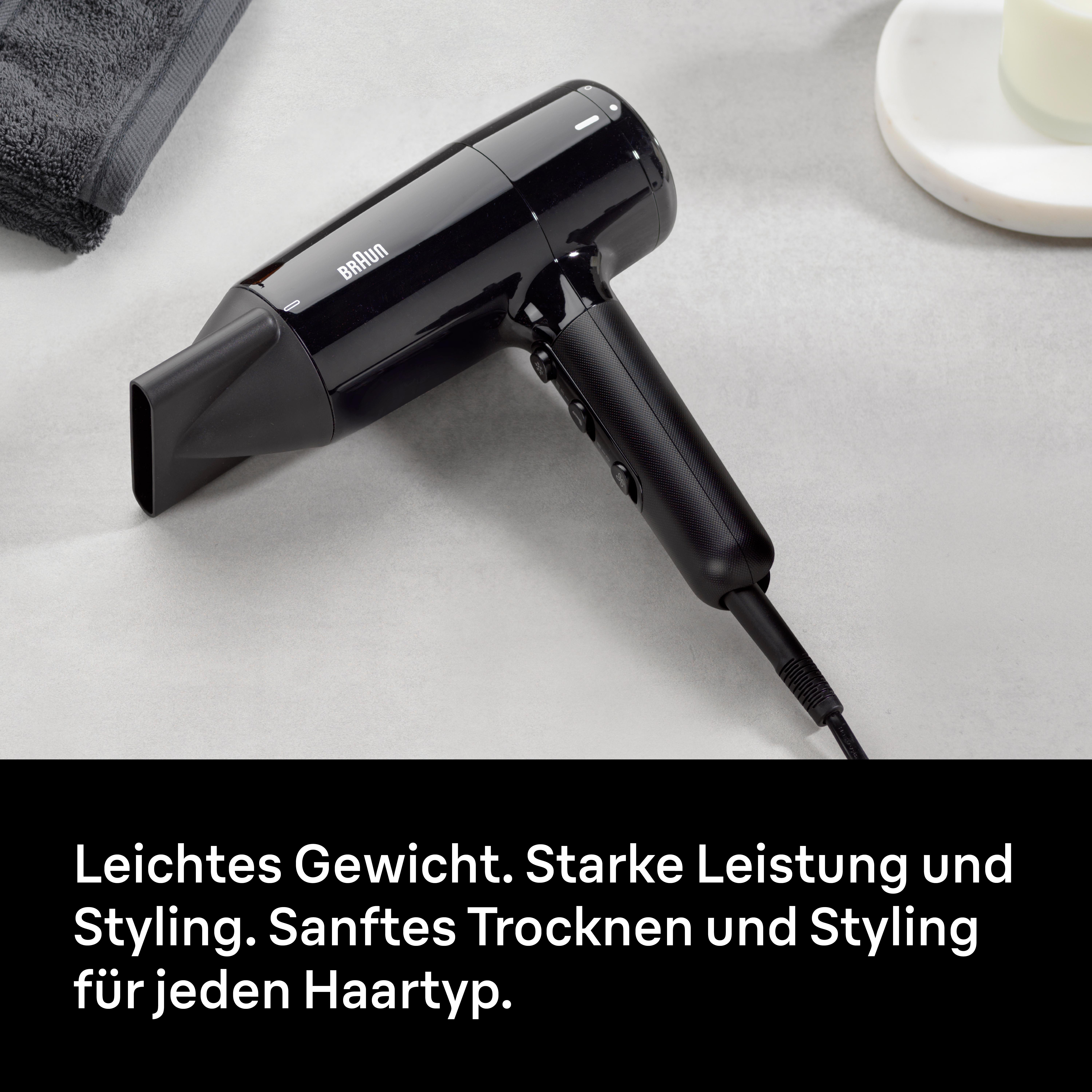 Schwarzer Braun-Haartrockner auf grauem Untergrund, mit Handtuch und Seifenschale. Text unten.