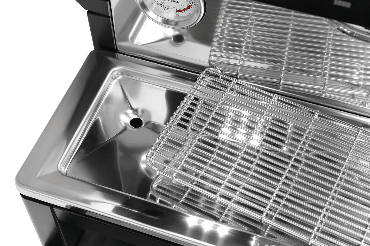 Nahaufnahme eines Edelstahlgrills mit Thermometer. Ein Metallrost befindet sich im Grill, umrahmt von einem schwarzen Rahmen.