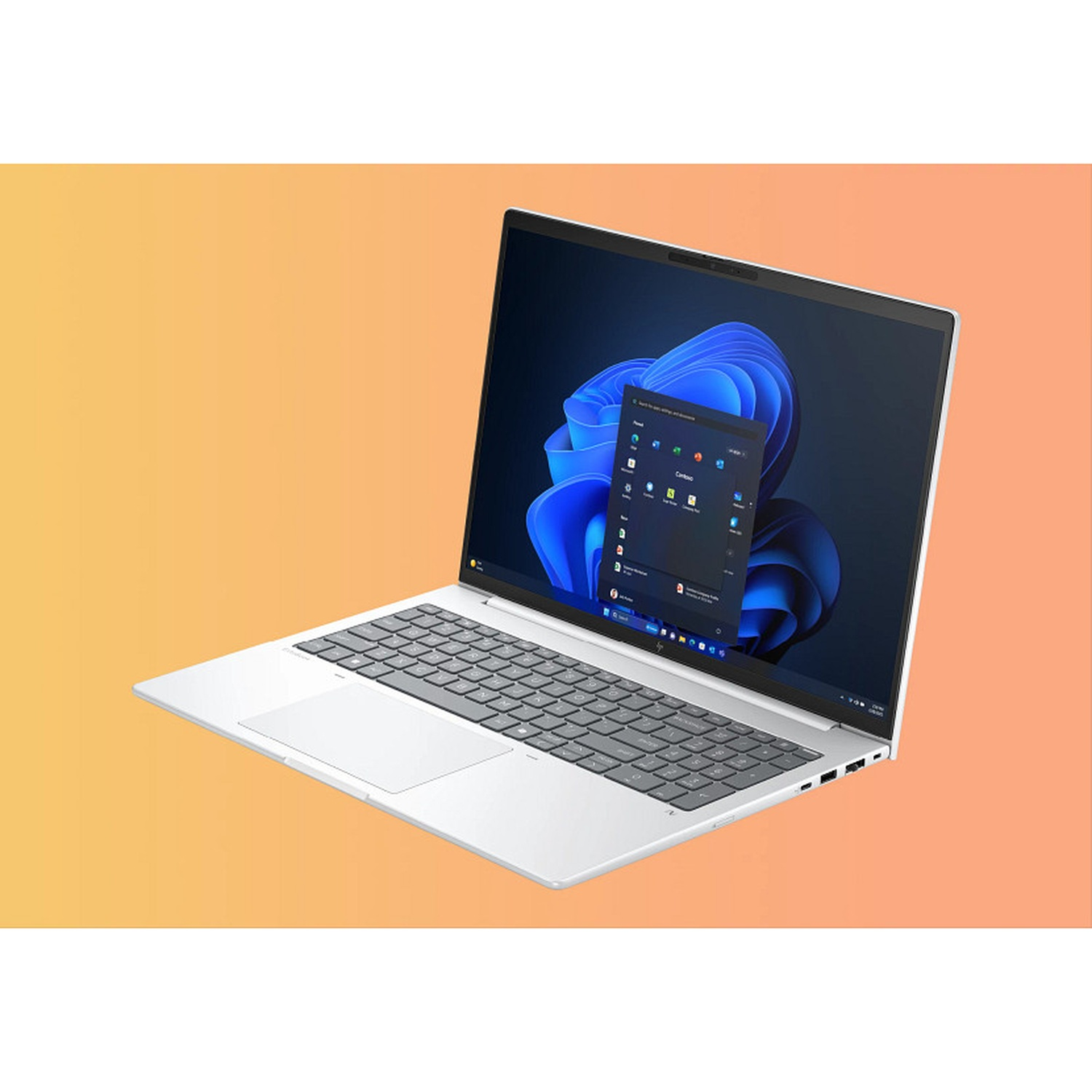 A white laptop is open on a gradient orange background. The screen displays the Windows 11 interface. The keyboard and touchpad are visible.