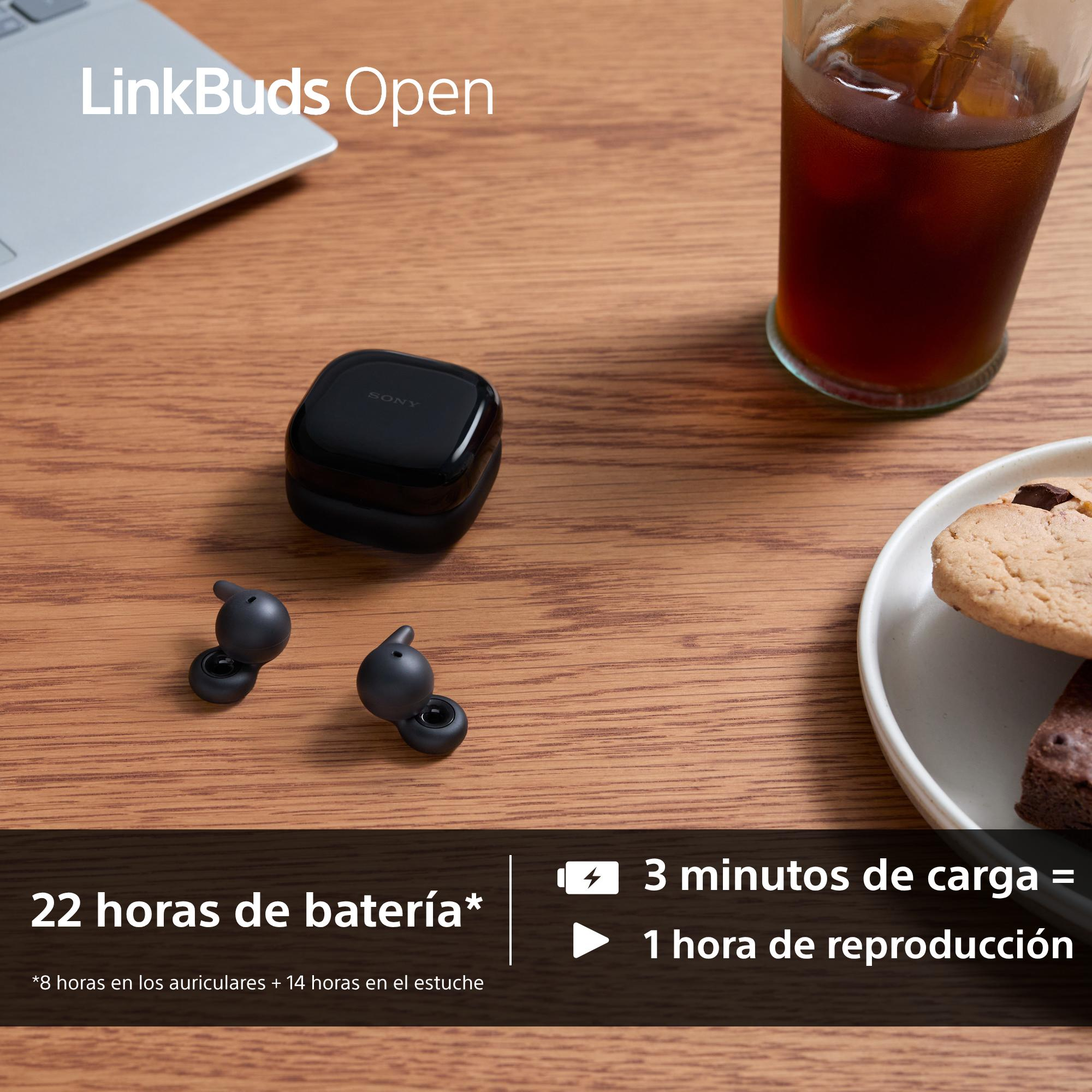 Auriculares y estuche negros de Sony sobre una mesa de madera, junto a una bebida y galletas. El texto muestra la duración de la batería.