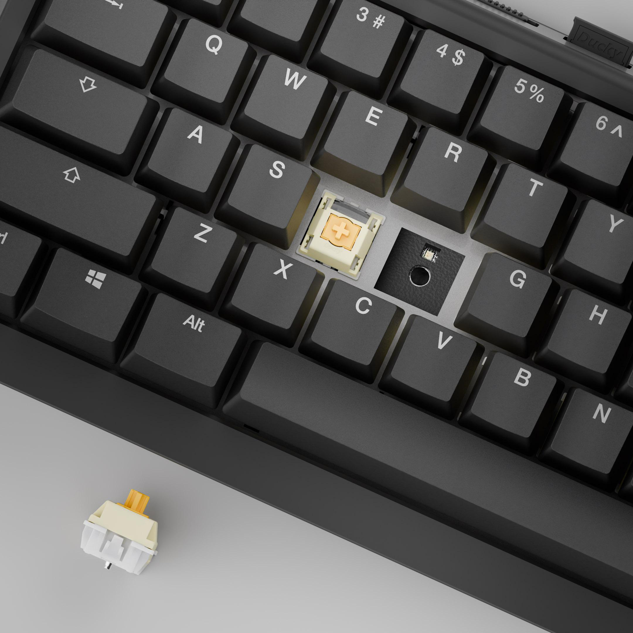 Nahaufnahme einer schwarzen Tastatur mit entfernter Taste, die einen Schalter zeigt. Ein weiterer Schalter befindet sich daneben. Grauer Hintergrund.