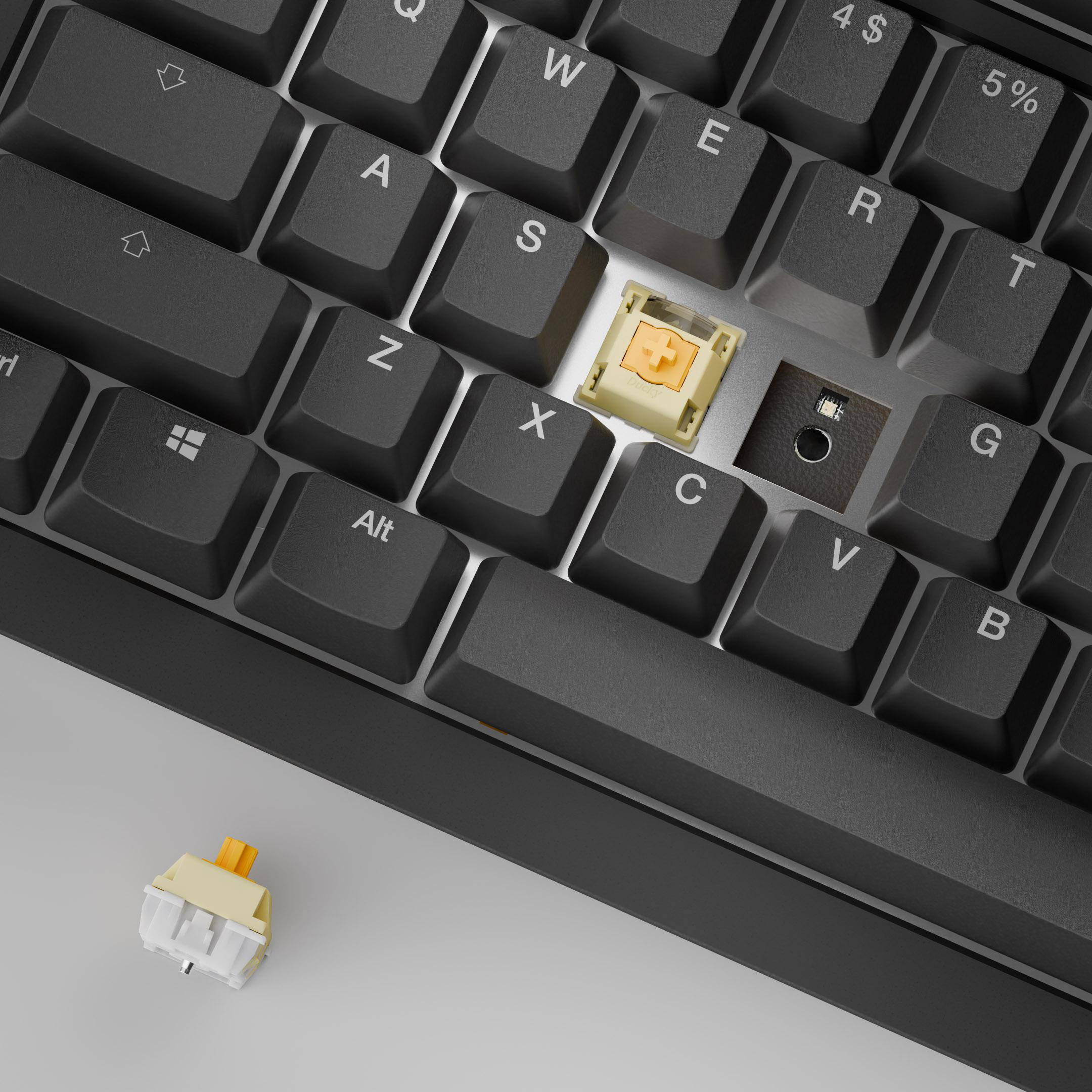 Nahaufnahme einer schwarzen Tastatur. Eine Taste ist entfernt und gibt den Schalter frei. Ein zusätzlicher Schalter liegt darunter.