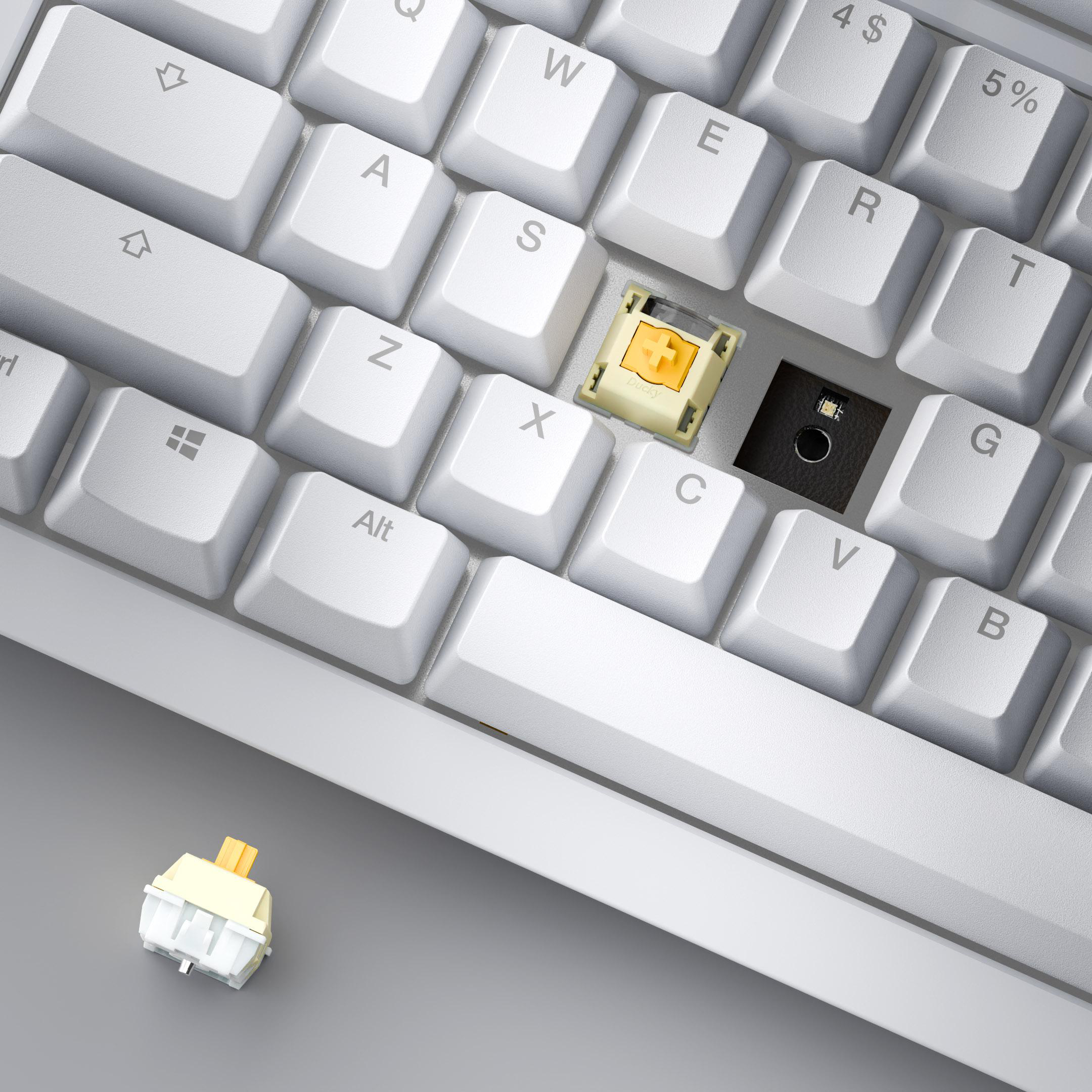 Nahaufnahme einer weißen Tastatur mit einem gelben Schalter. Tasten sind sichtbar, darunter W, E, R und G.