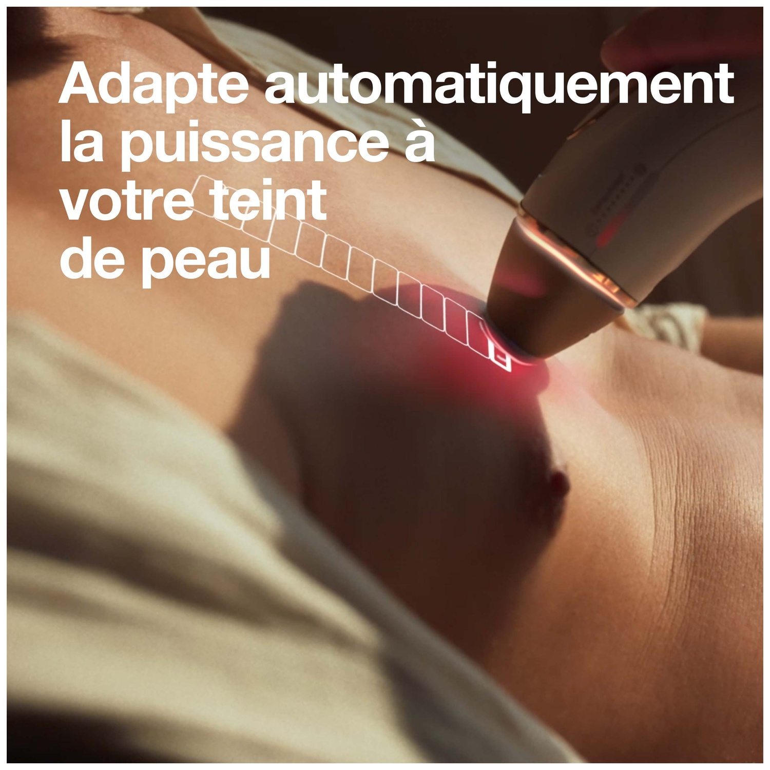 Un appareil émettant une lumière rouge est utilisé sur la peau. Le texte indique qu'il adapte la puissance au teint. La peau est brun clair.