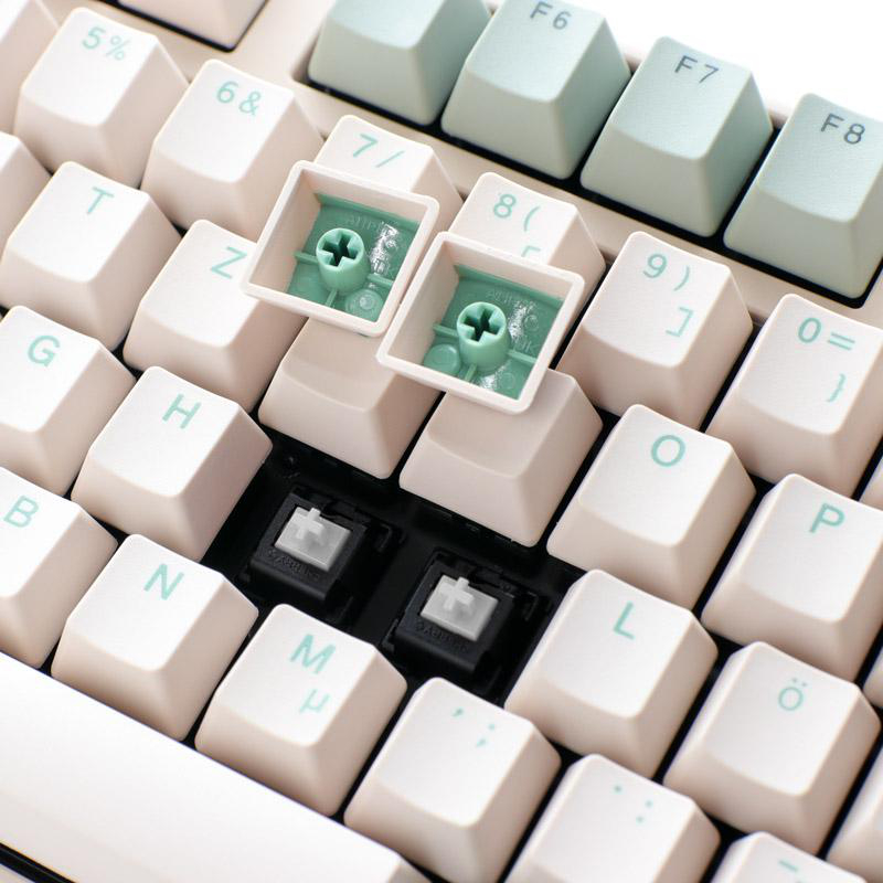 Nahaufnahme einer mechanischen Tastatur. Tastenkappen sind abgenommen, Schalter sind sichtbar. Weiße und hellgrüne Tasten mit Symbolen und Buchstaben.