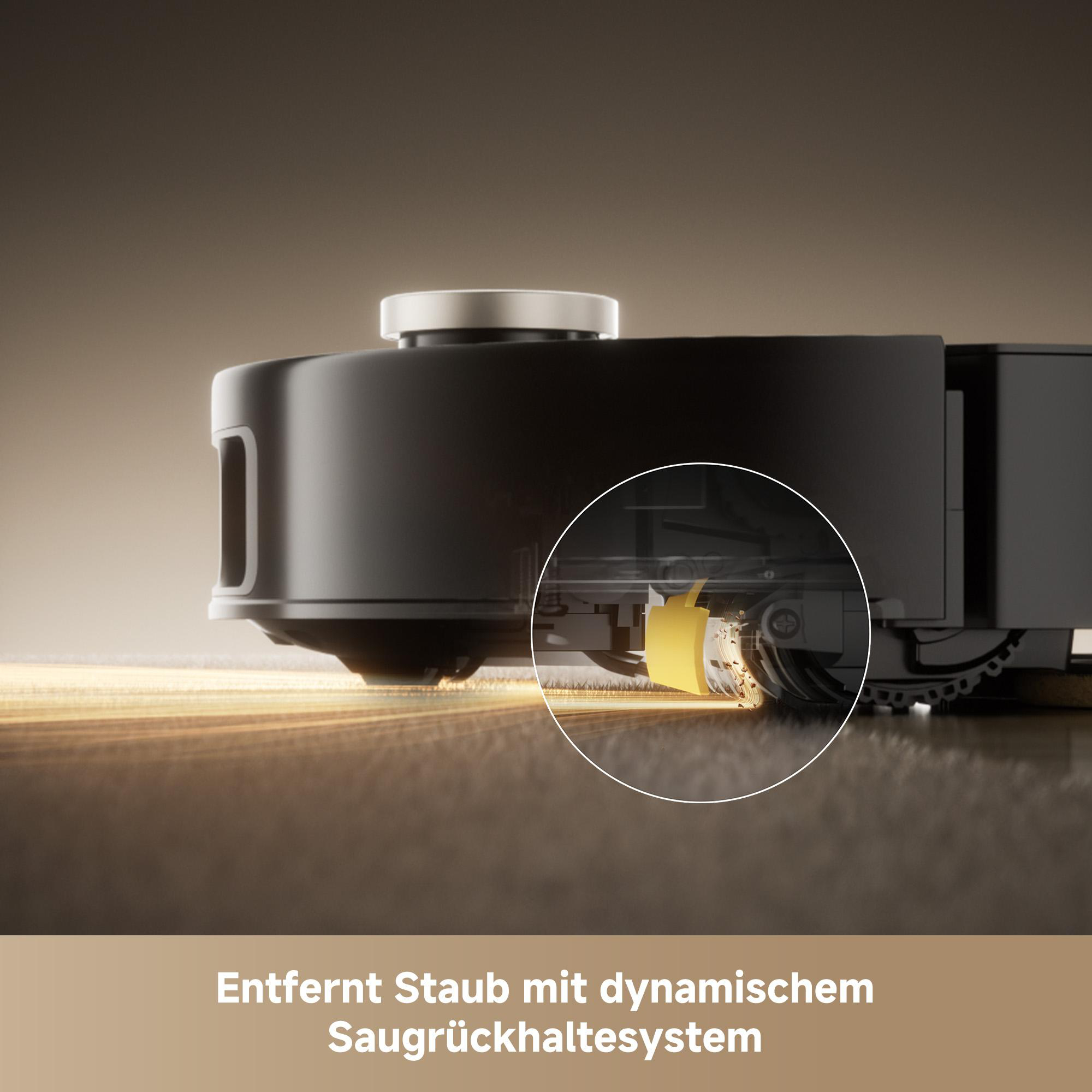Ein schwarzer Roboter-Staubsauger mit gelber Komponente. Staubpartikel zeigen den Reinigungsvorgang.