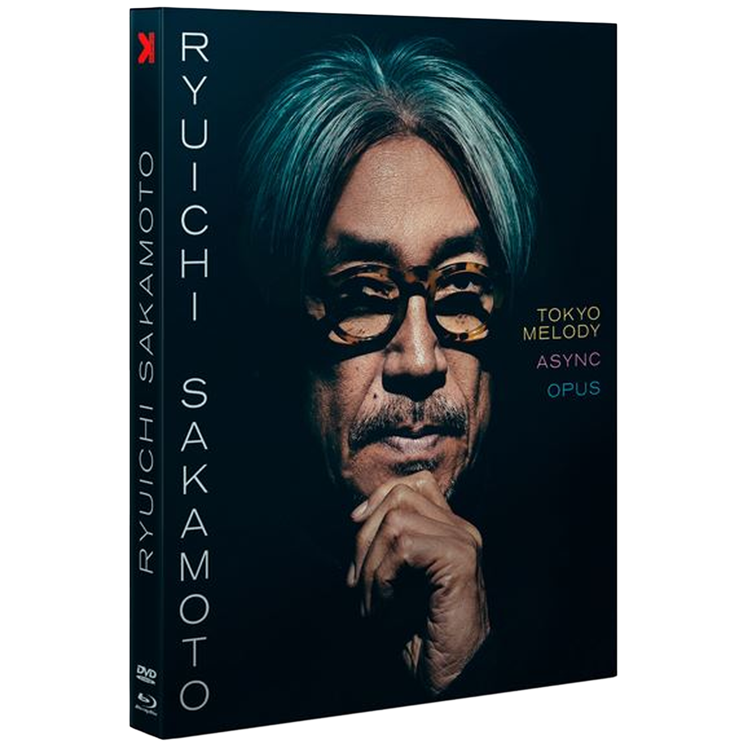 Couverture de DVD. Un homme avec des lunettes, les cheveux clairs et une moustache. Le texte indique 'Ryuichi Sakamoto', 'Tokyo Melody Async Opus'.
