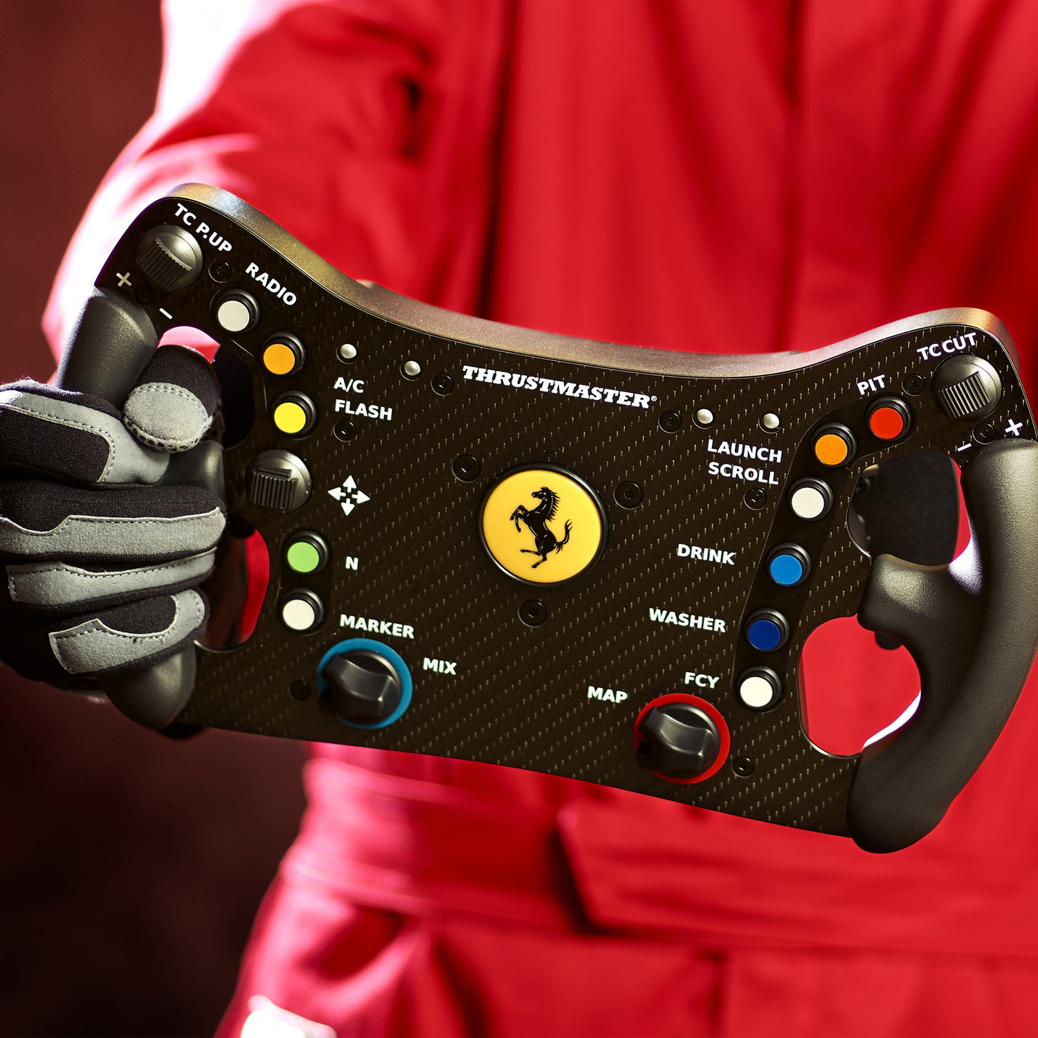 Une personne en combinaison rouge tient un volant Ferrari. Le volant a divers boutons et le logo Ferrari.