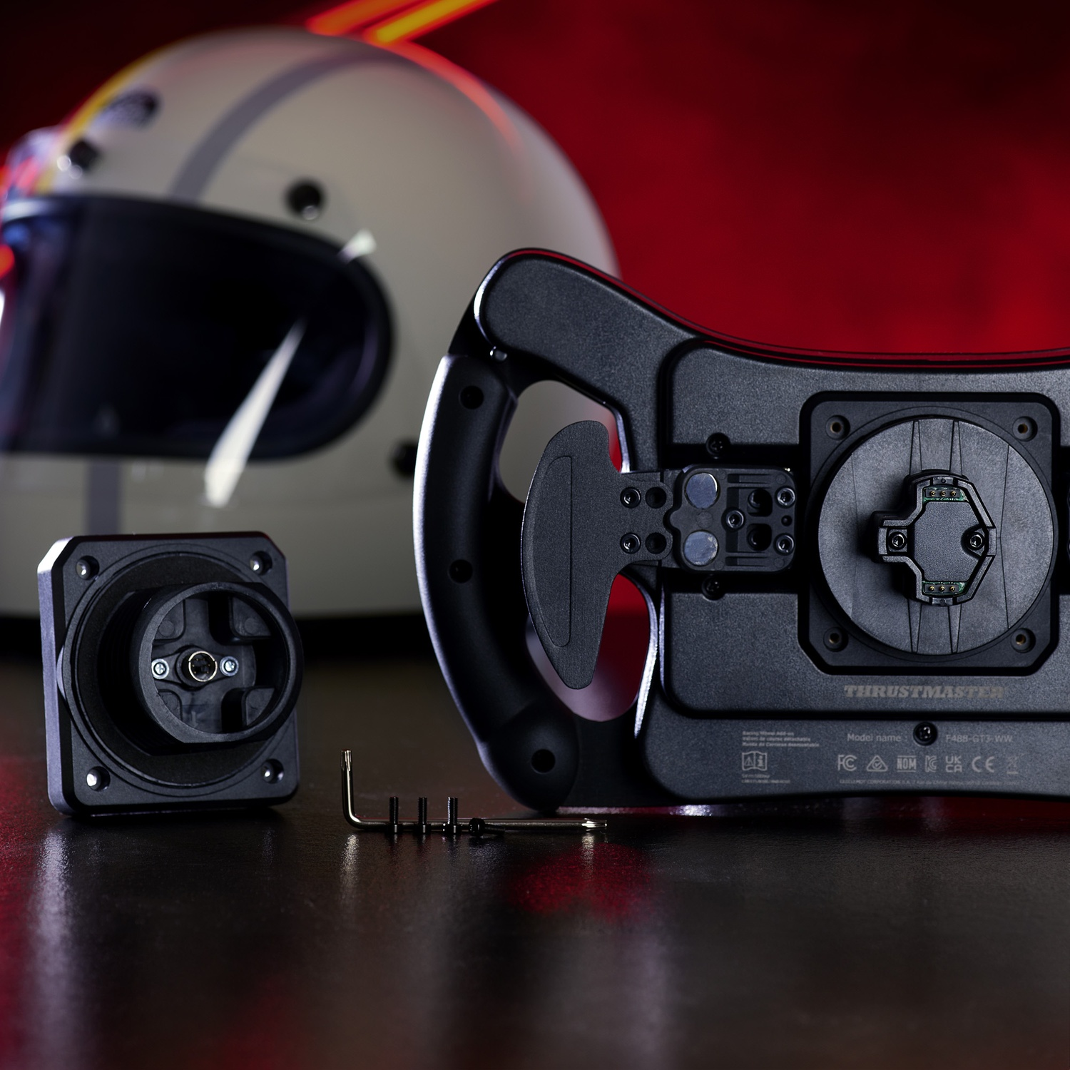 Volant de course, casque et composants sur une surface sombre. Le volant et les composants sont noirs. Le casque est blanc.