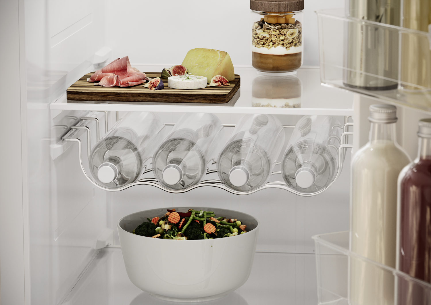 Dentro de un refrigerador: comida en estantes, incluyendo queso, higos, botellas, un cuenco de verduras y un tarro de granola.