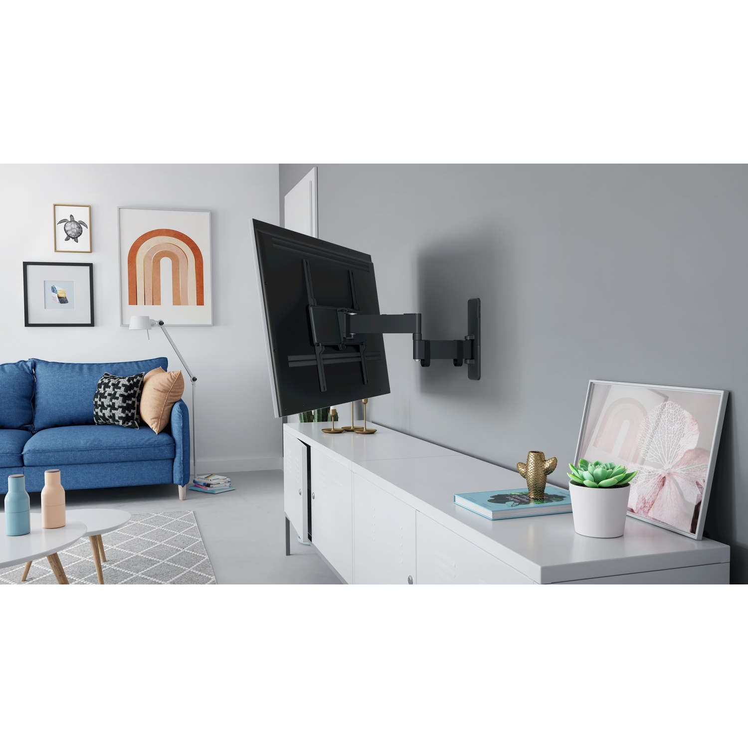 Woonkamer met tv aan grijze muur. Een blauwe bank, witte kast en ingelijste kunst zijn zichtbaar.