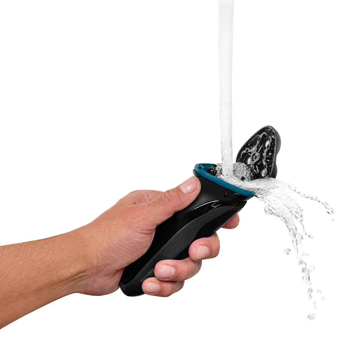 Una mano sostiene una afeitadora eléctrica negra y verde azulado, el agua se vierte en ella. El fondo es blanco.