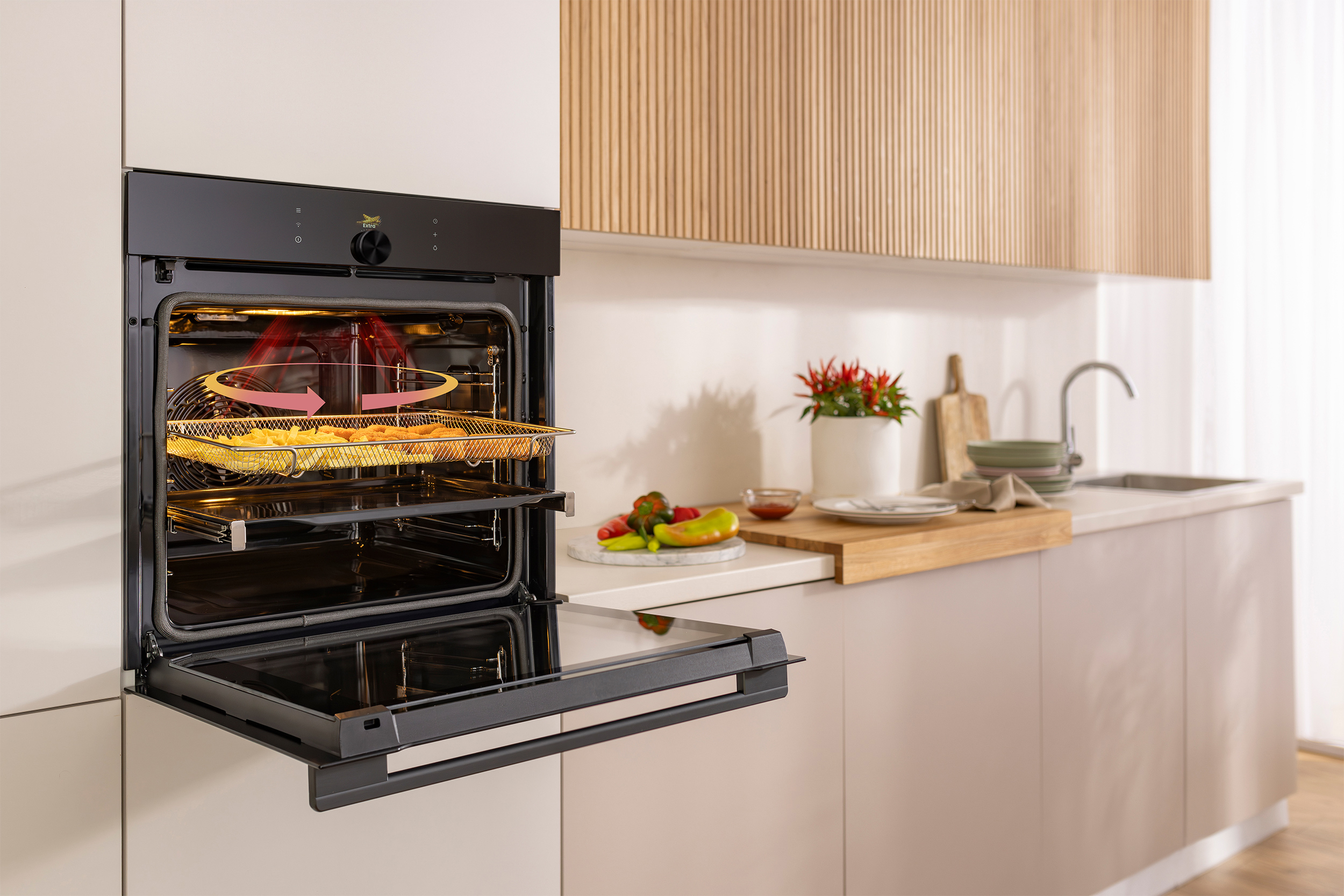 Open oven with food inside. Kitchen counter with food and sink. Light wood and white cabinets.