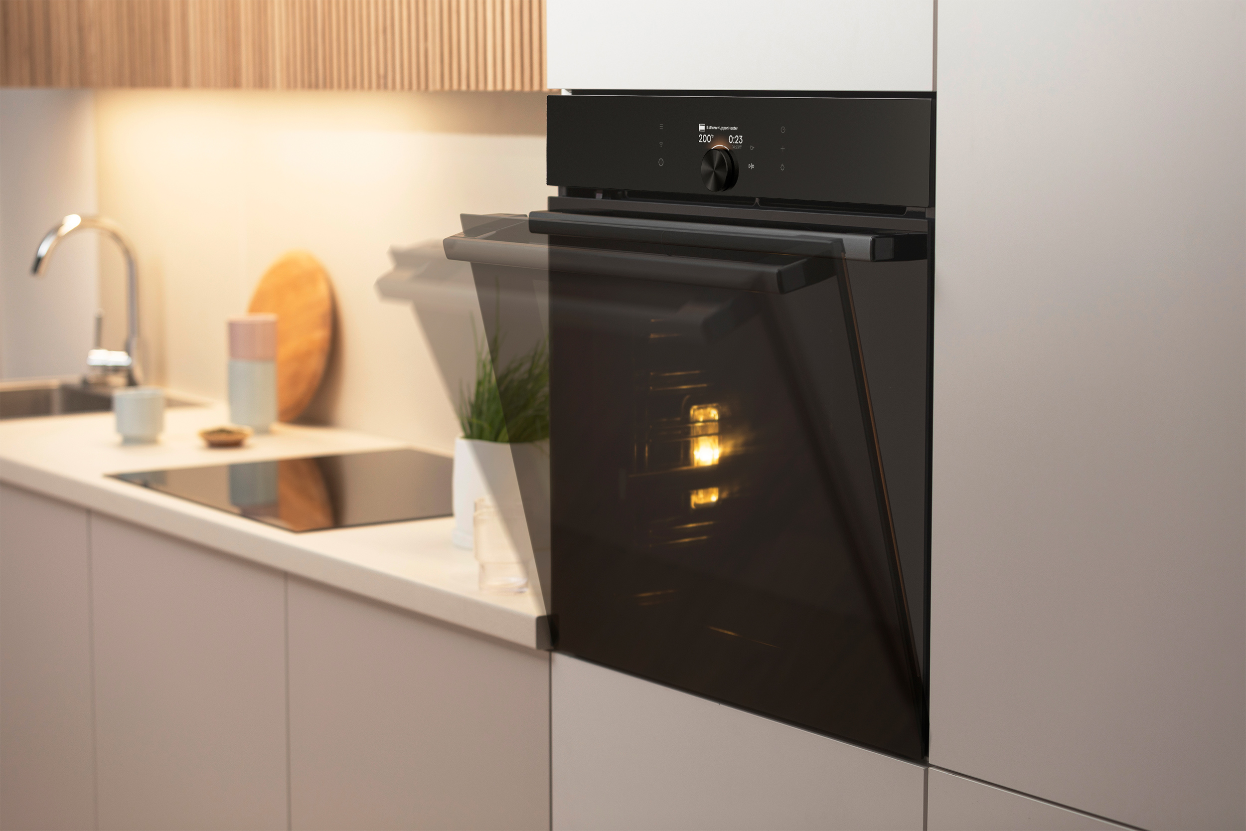 A kitchen scene with an oven, a sink, and decorative items on the counter. The oven door is slightly open.