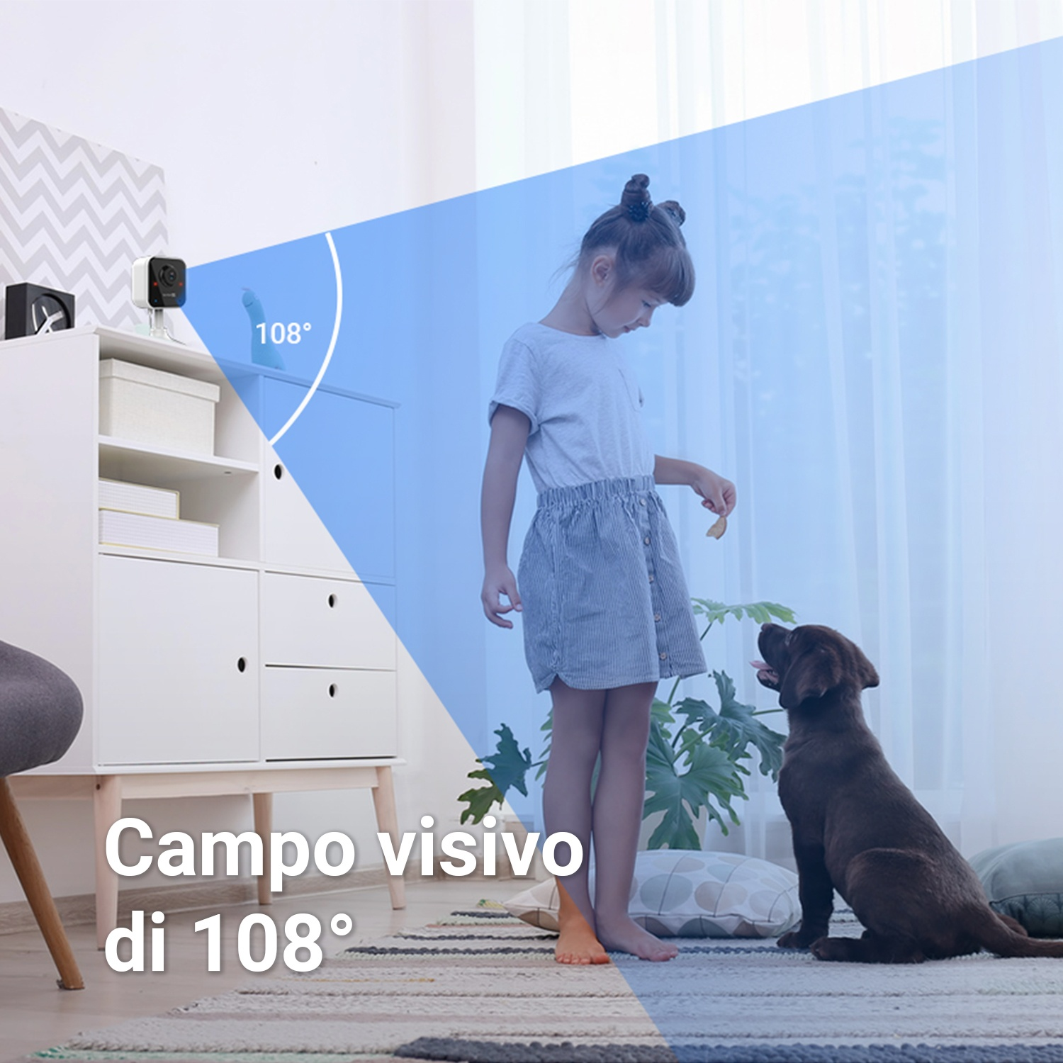 Una ragazza dà un premio a un cane marrone. Una telecamera di sicurezza è su un mobile bianco. La visuale è di 108 gradi.