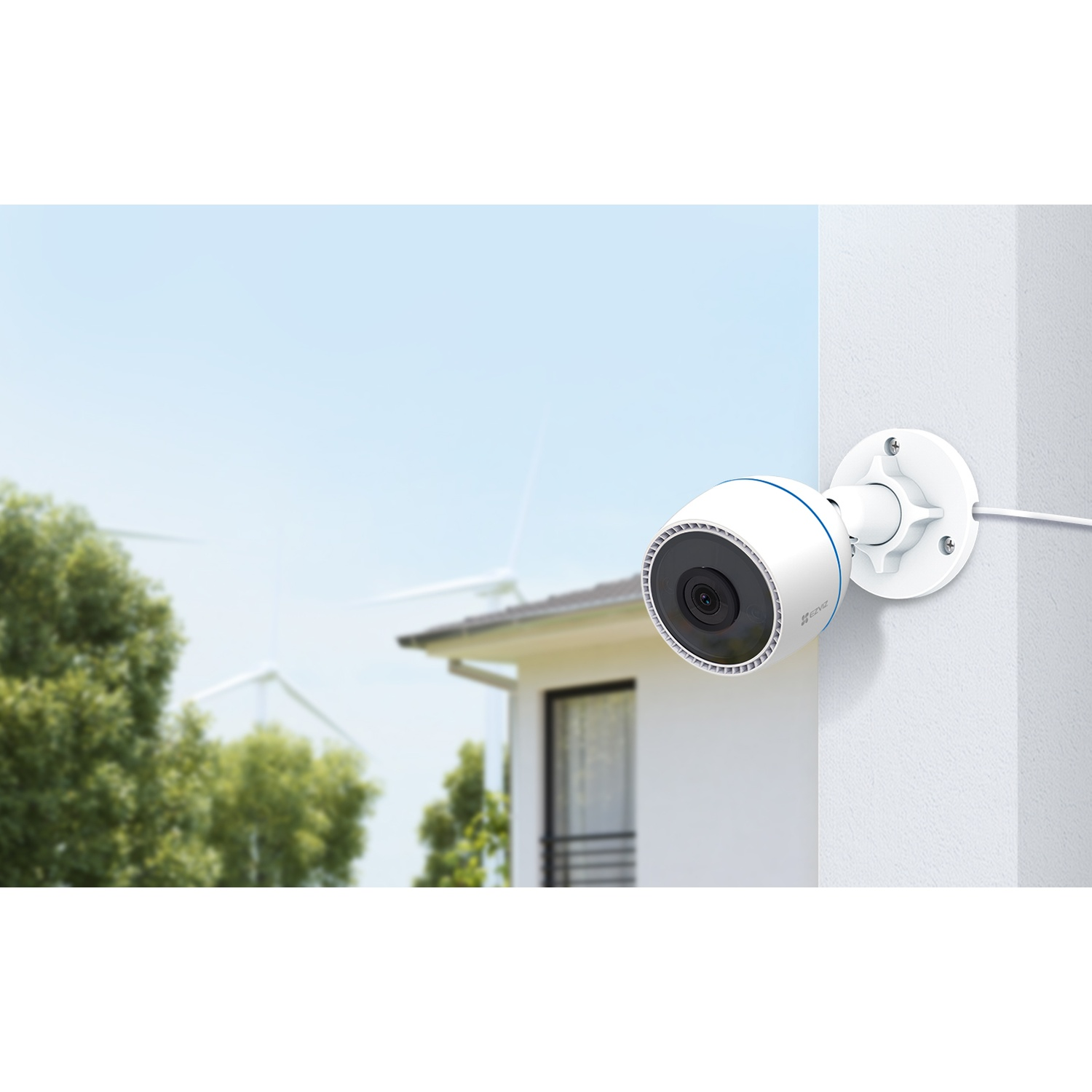 Una telecamera di sicurezza bianca con una striscia blu è montata su un muro bianco. Lo sfondo mostra una casa, alberi e mulini a vento.