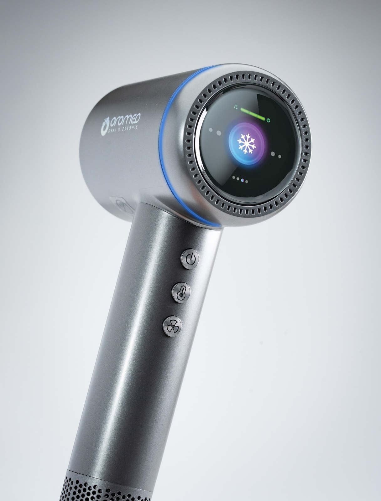 Srebrna suszarka do włosów z niebieskimi akcentami. Posiada cyfrowy ekran z ikoną płatka śniegu. Trzy przyciski na uchwycie.