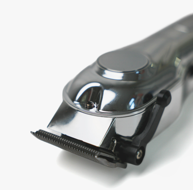 Zbliżenie srebrnej maszynki do włosów na białym tle. Ostrze maszynki jest ostre, z czarną dźwignią.