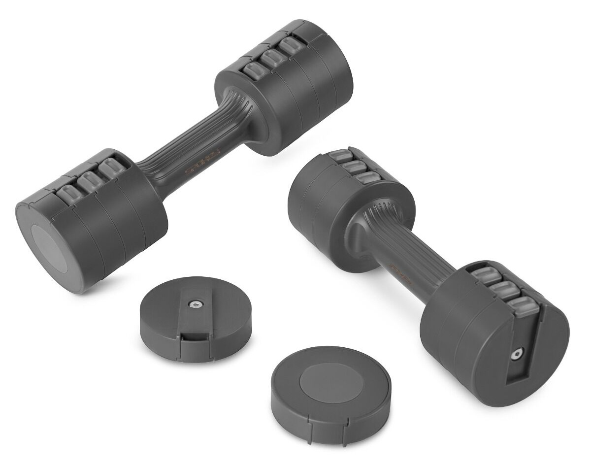Dwie szare hantle i dwa okrągłe ciężarki na białej powierzchni. Hantle są w pozycji pochylonej.