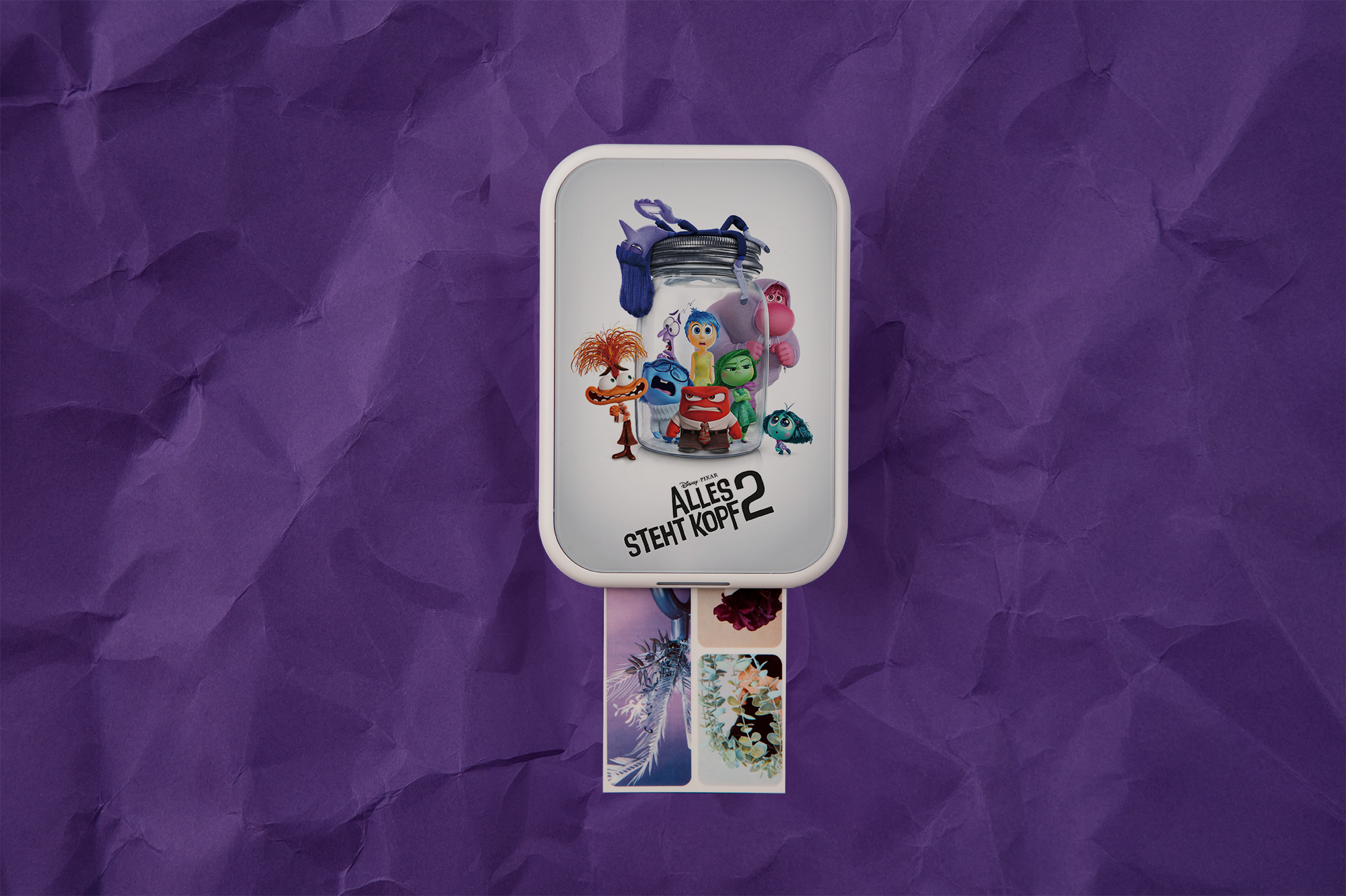 Inside Out 2 Poster. Charaktere in einem Glas auf lila Hintergrund. Fotos werden von einem Gerät gedruckt.