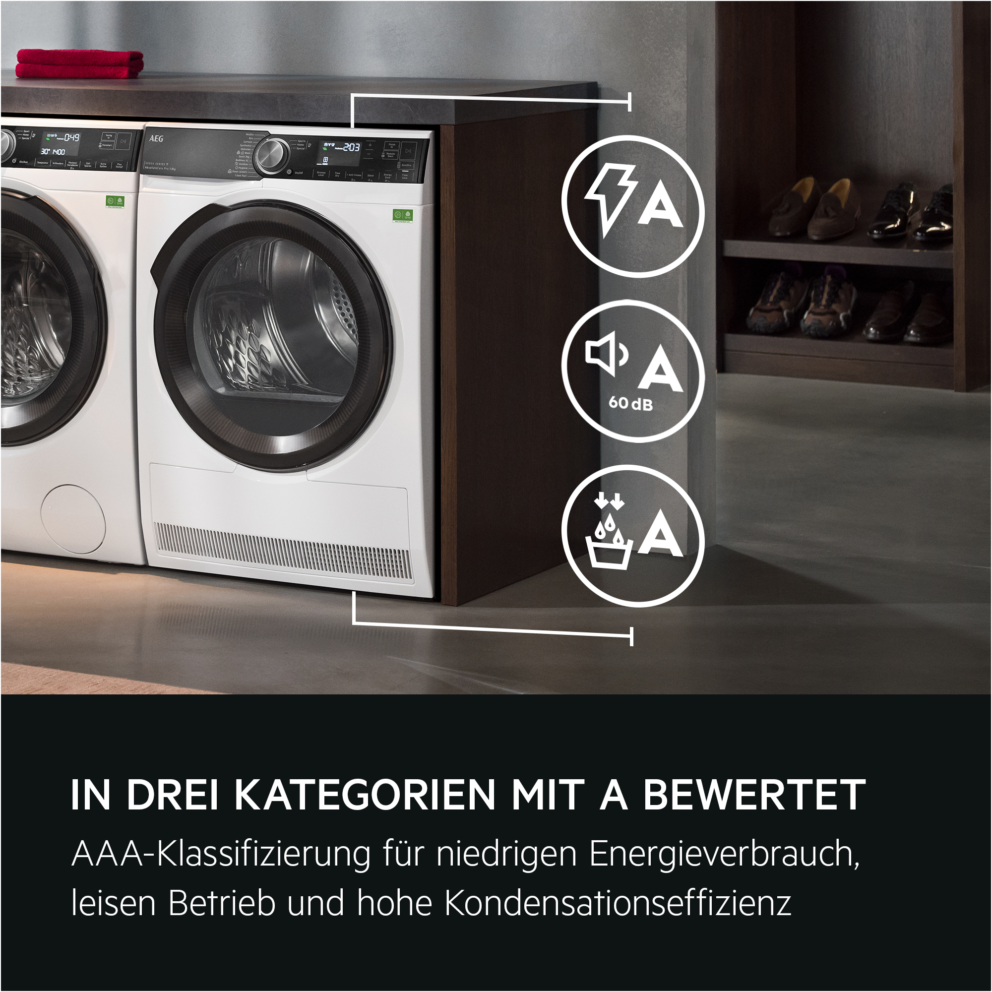 Weiße Waschmaschinen mit schwarzen Akzenten, rotes Handtuch, Symbole und Schuhe auf Regalen sichtbar.