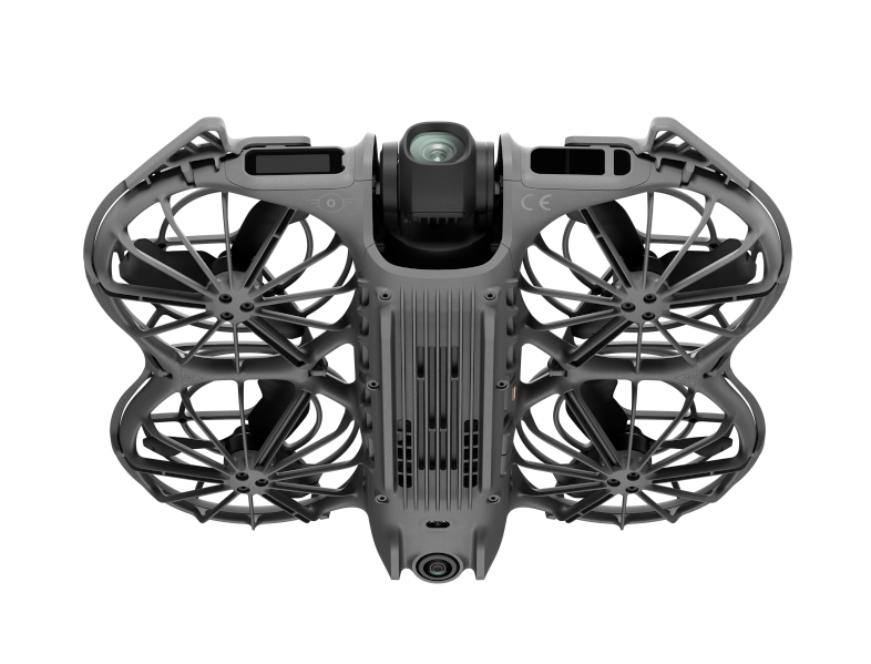 Szary dron z czterema śmigłami. Kamera jest widoczna z przodu. Dron jest na czarnym tle.