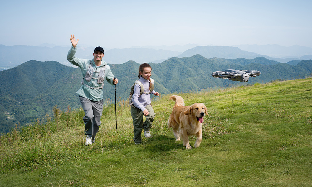 Mężczyzna i dziewczyna wędrują z psem po trawiastym wzgórzu, dron w powietrzu. Góry w tle.